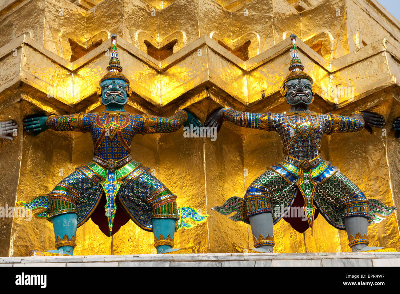 Demons guard the bottom of a gilded chedi, at the temple of the Emerald  Buddha (Wat Phra Kaeo), Grand Palace, Bangkok, Thailand Stock Photo