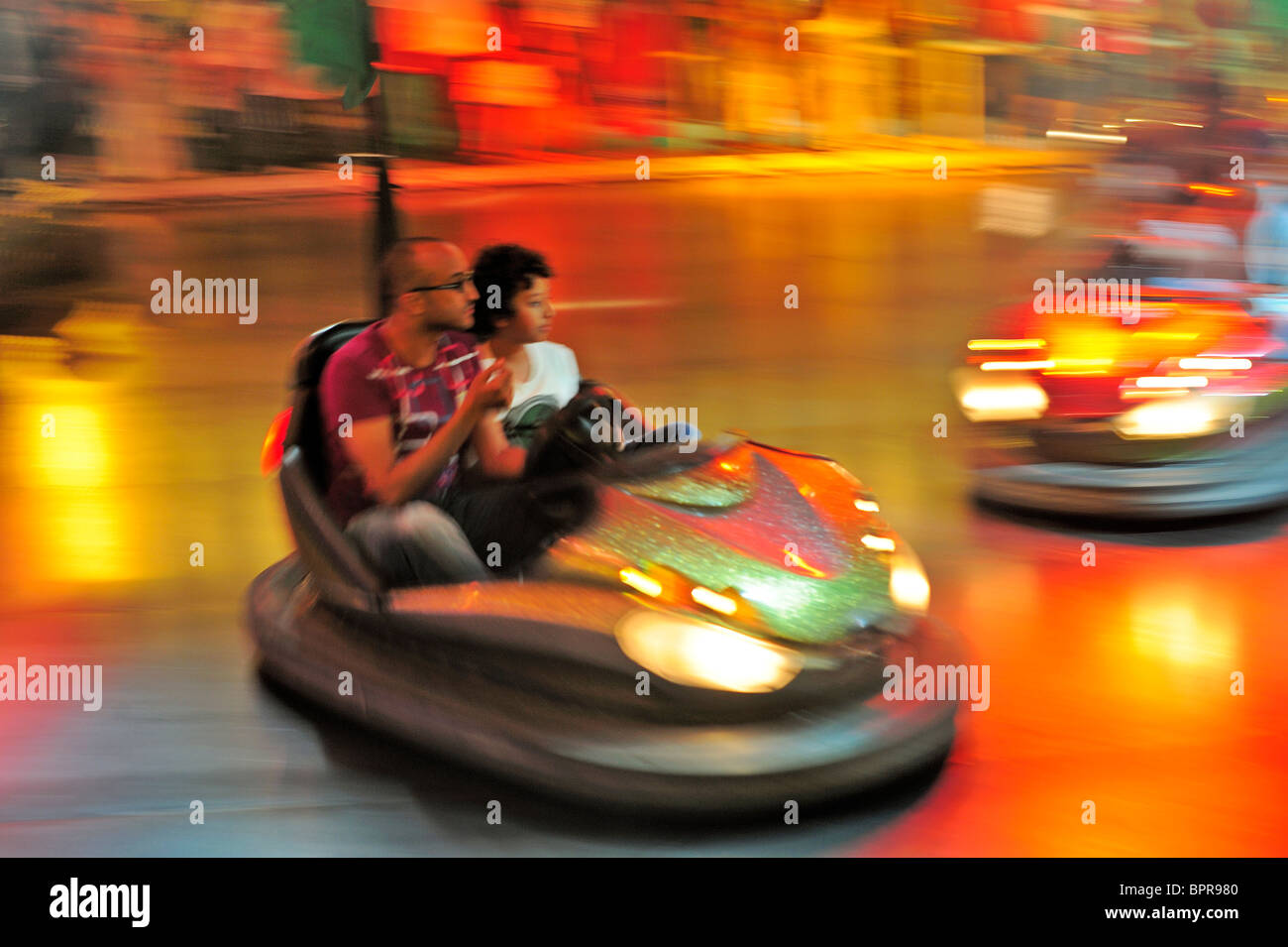 On the dodgems (bumper cars) in a fairground at night. Motion blur used