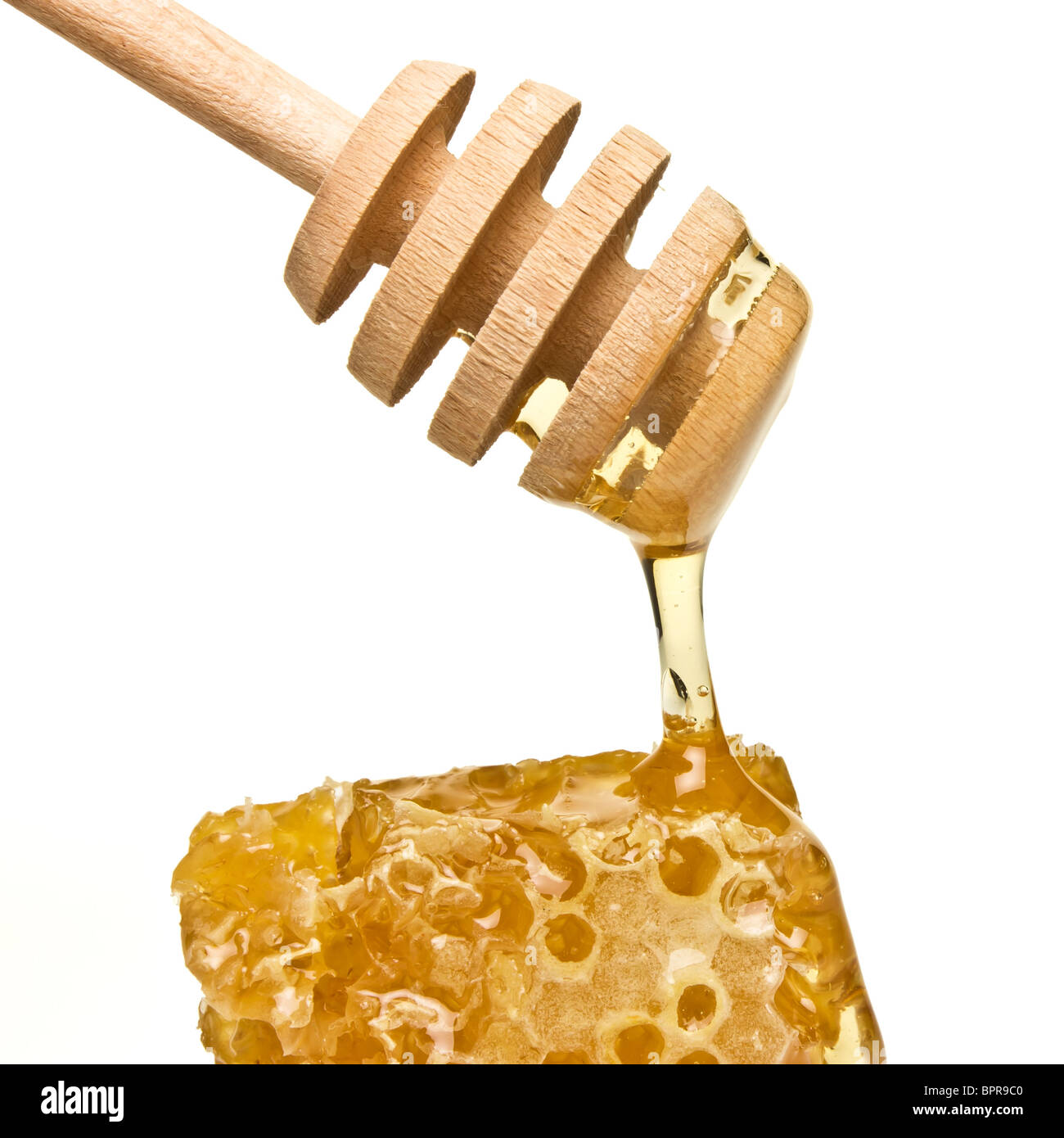 Natural Honey dripping from wooden drizzler isolated on white. Stock Photo