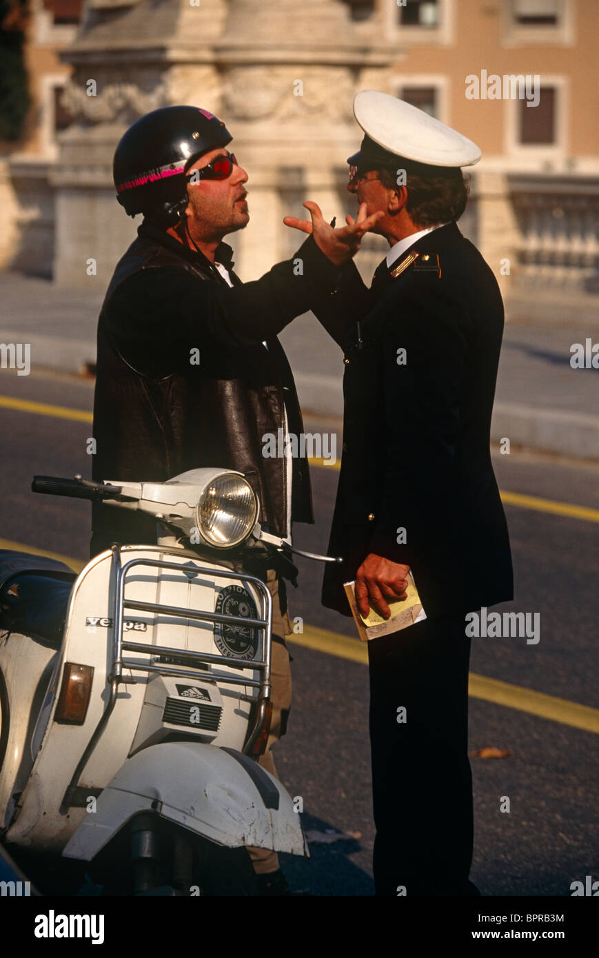 A typical argument of gestures and angry body language between a Vespa scooter rider and traffic policeman. Stock Photo