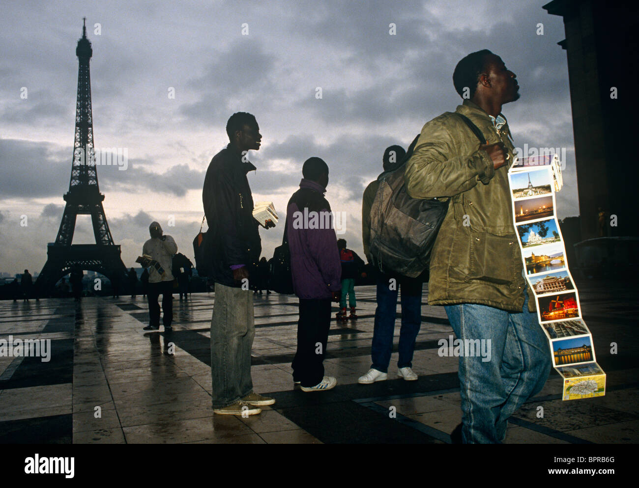 African street vendors wait for coach tourists to sell postcards near the Eiffel Tower, at the Trocadero, Paris. Stock Photo