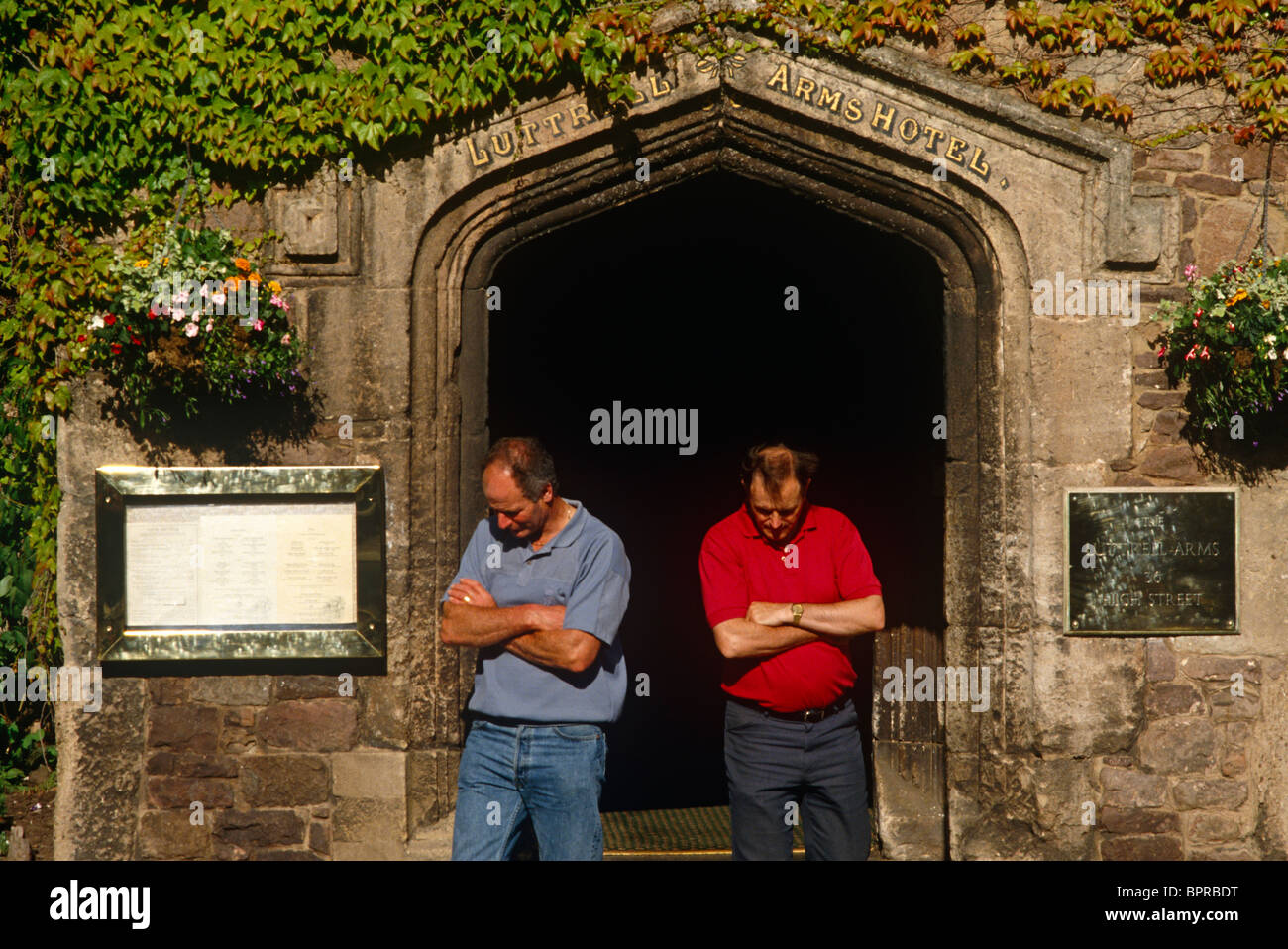 Two men emerge from the Luttrell Arms,their own arms folded in postural