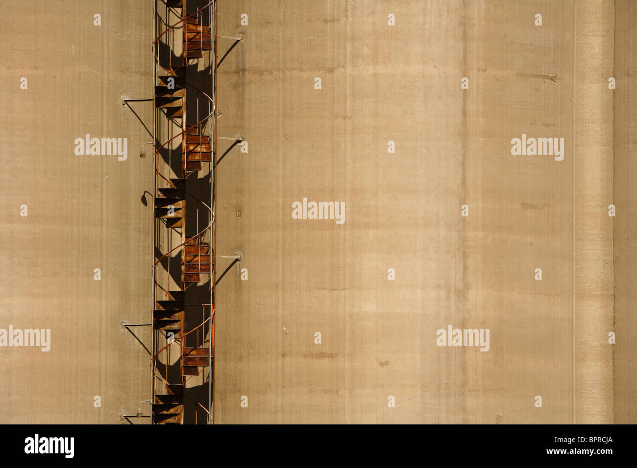 Rusted spiral staircase climbs the exterior of a large concrete silo in downtown Charleston, WV. Stock Photo