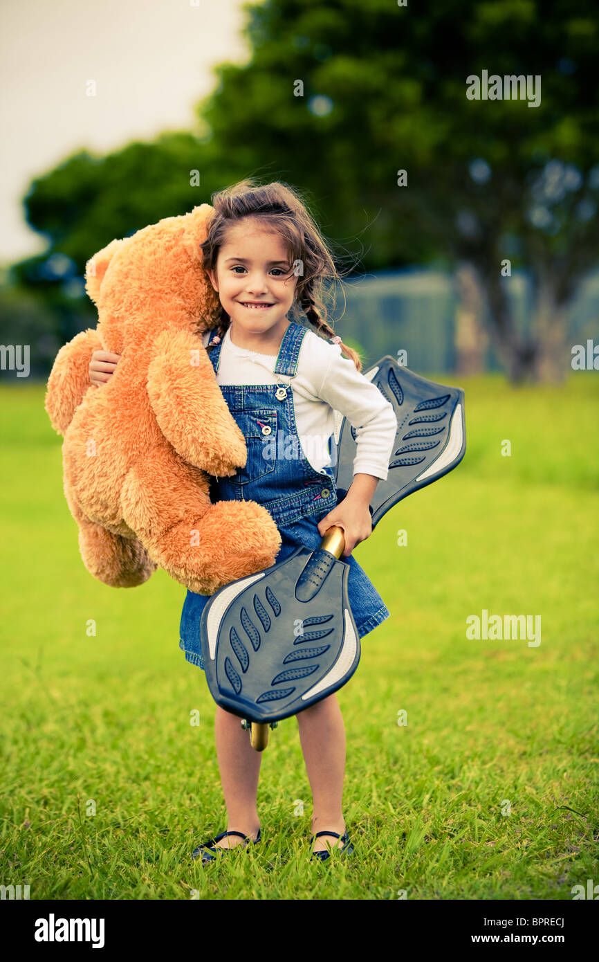 Little cute girl standing in the grass holding teddy bear Stock Photo ...