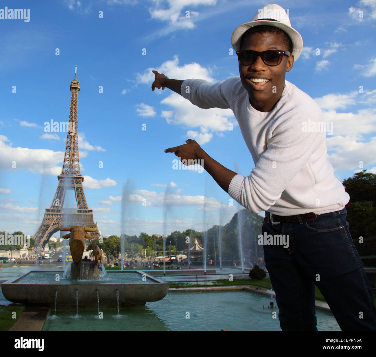 Black man pointing to the Eiffel tower, blue sky, Summer in Paris Stock Photo