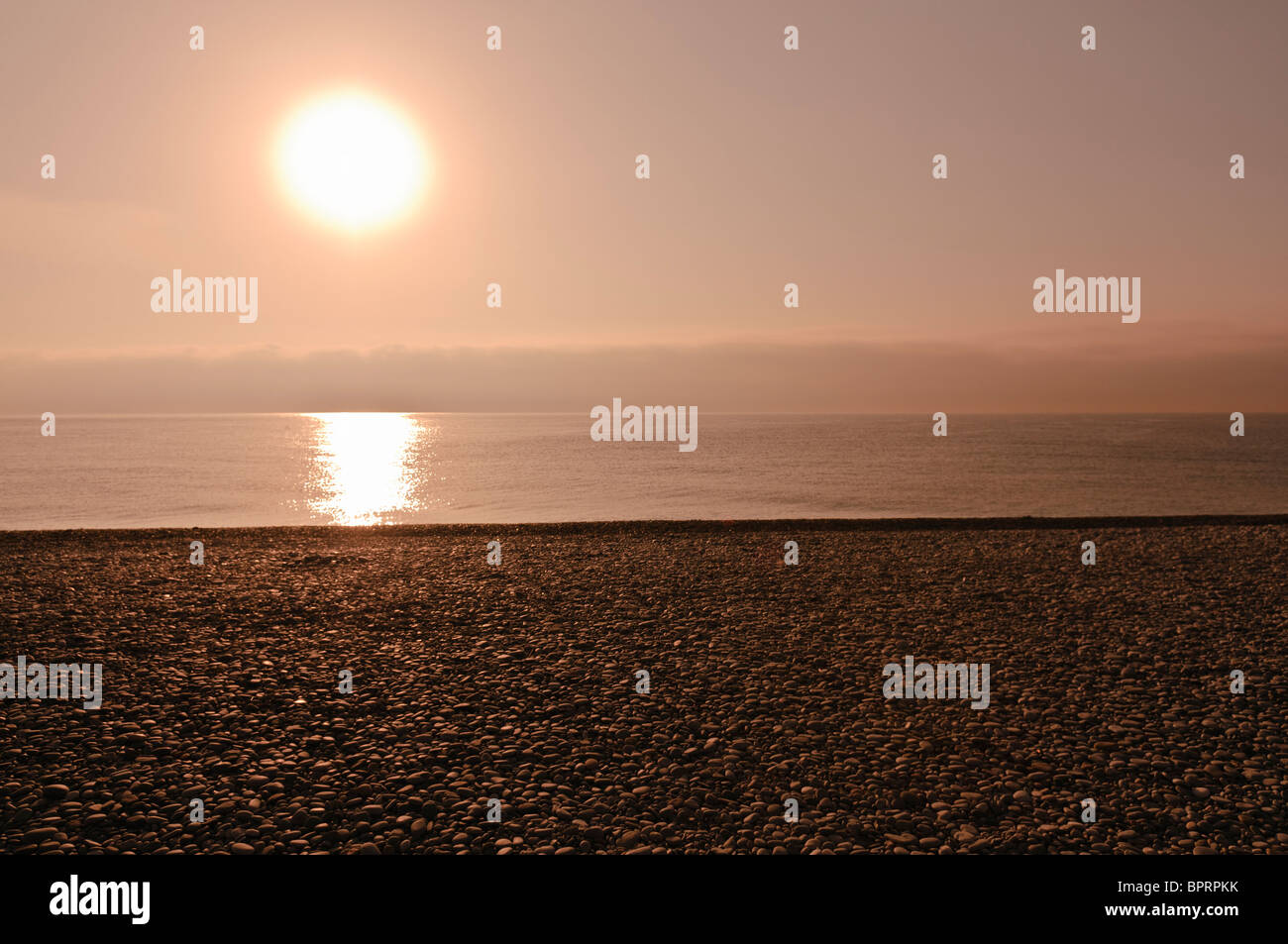 Sunrise over the sea and a pebble beach Stock Photo