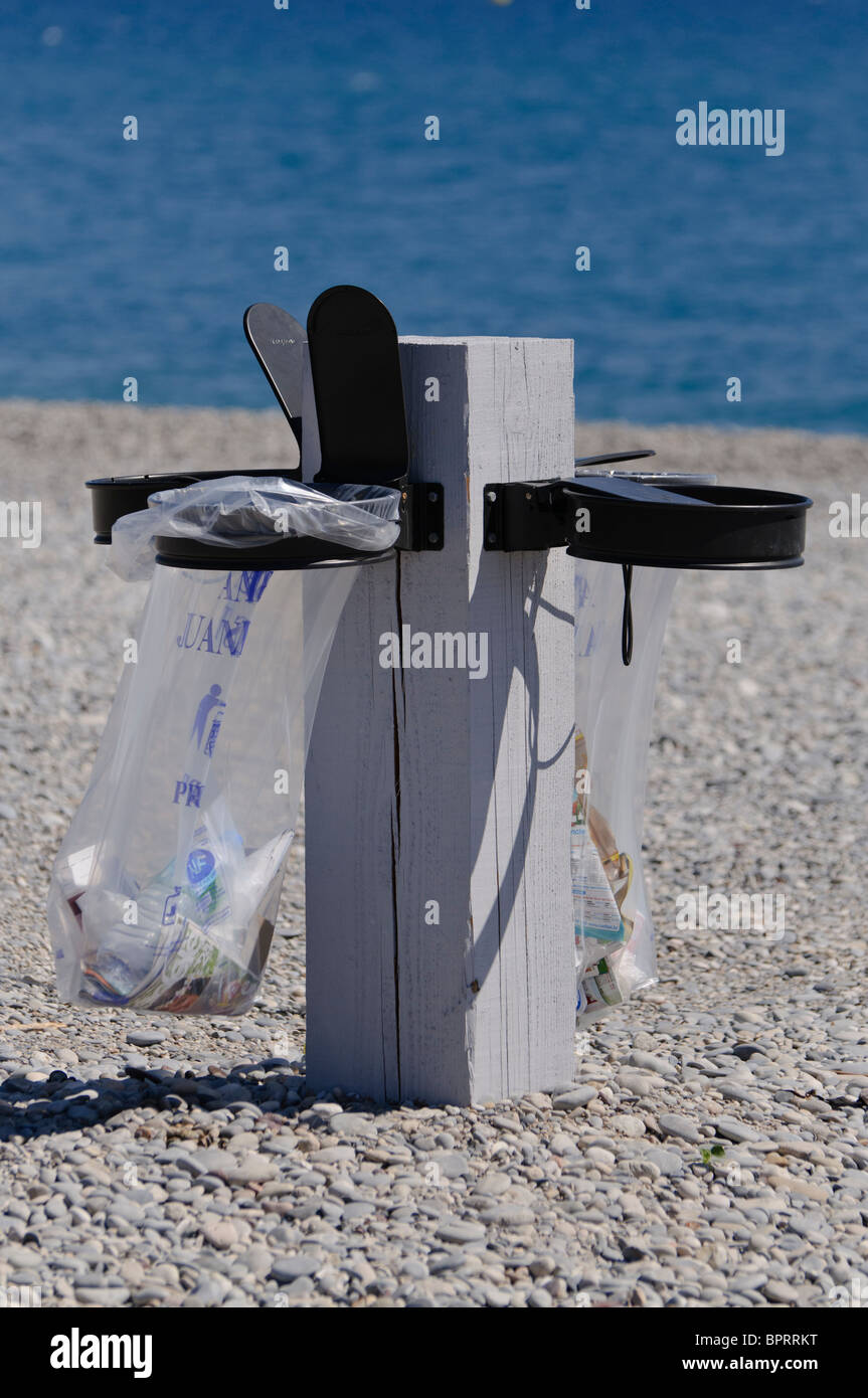 Plastic bag litter bins on a pebble beach at Antibes. Stock Photo