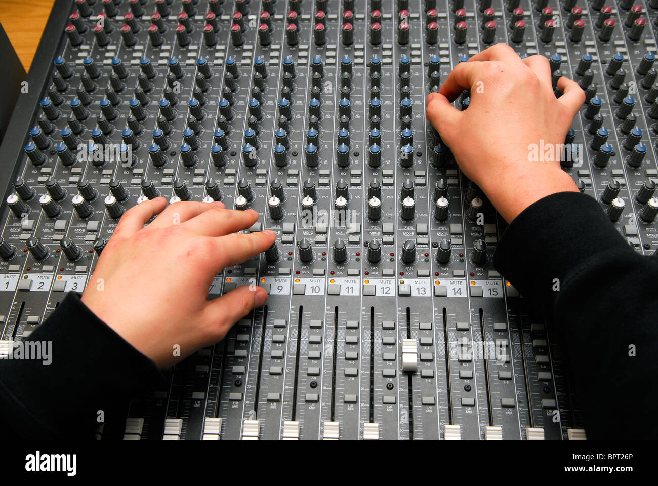 Young man adjusting sound levels in mixing suite at a music resource centre, Sherborne, Dorset, UK. Stock Photo