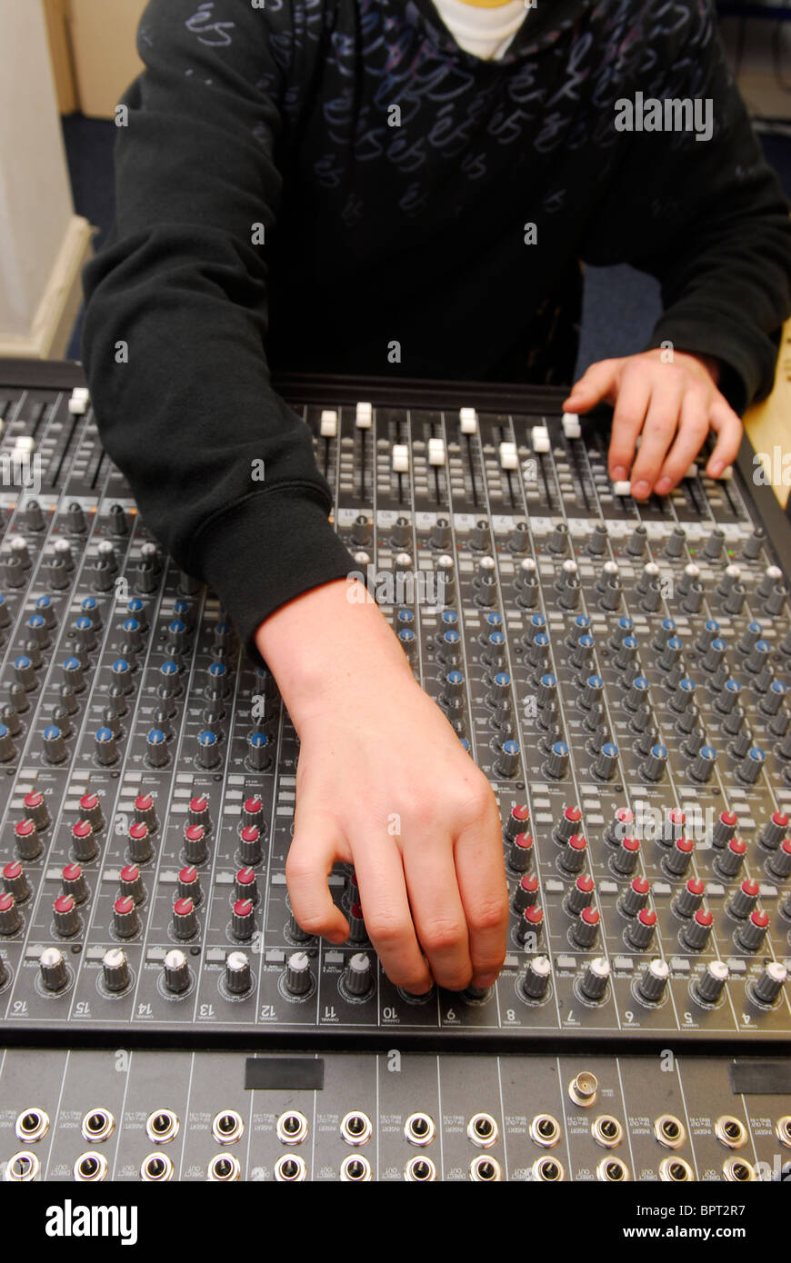 Young man adjusting sound levels in mixing suite at a music resource centre, Sherbourne, Dorset. Stock Photo