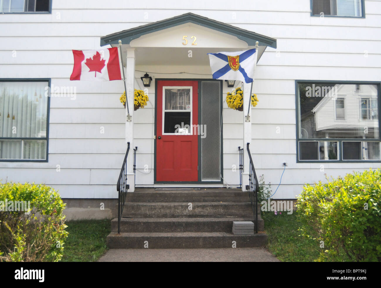 The flags of Nova Scotia and Canada are seen flying outside the home of a patriotic Canadian in Lunenburg, Nova Scotia, Canada. Stock Photo