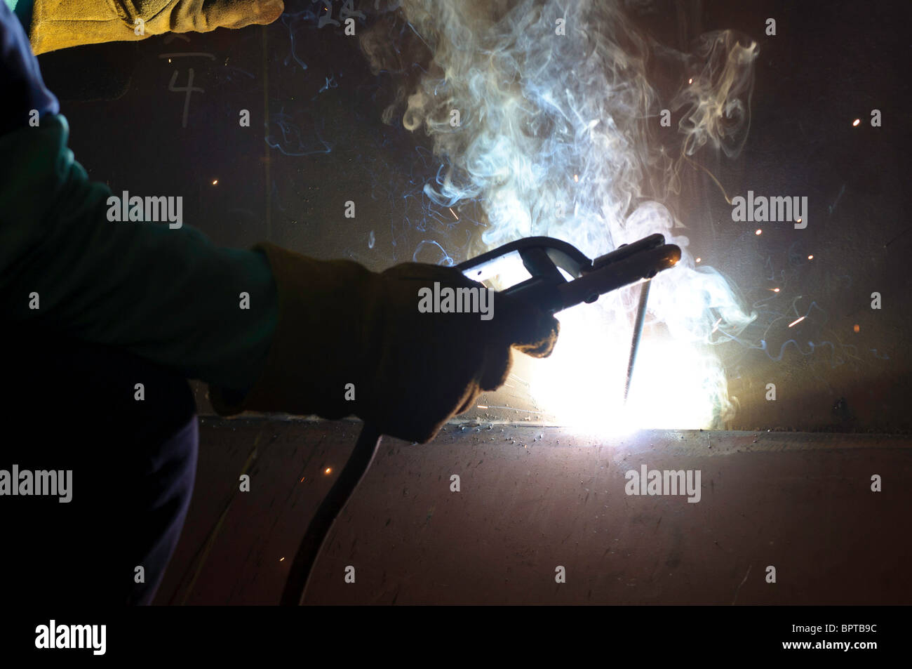 Detail shot of welding torch being used to weld steel plates Stock
