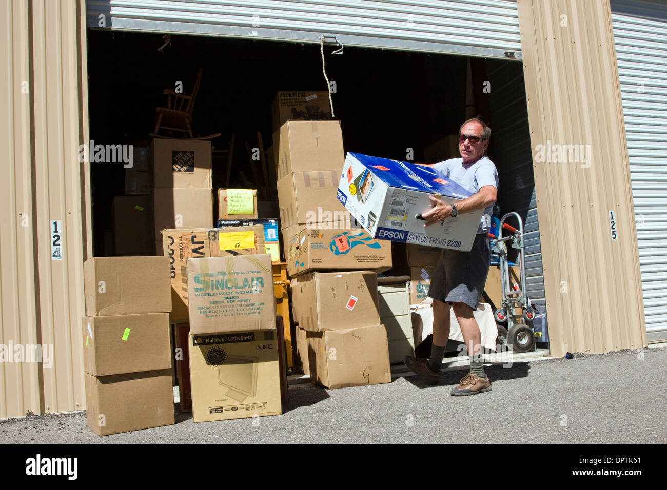 Man removing boxes of belongings from a self storage space. Stock Photo