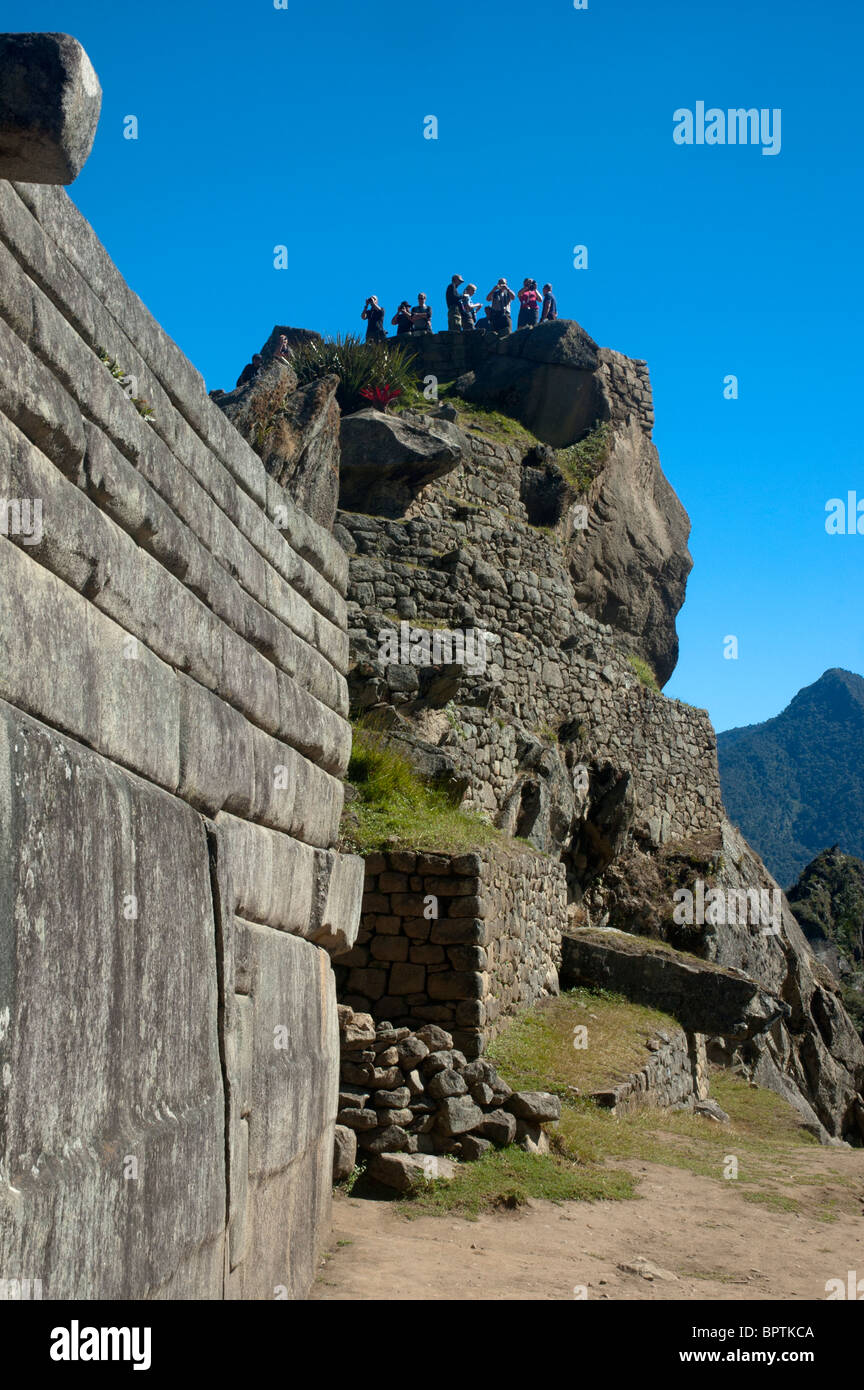 Tourists amidst the intricate stonework of ruined buildings at the ancient Incan city of Machu Picchu, Peru. Stock Photo