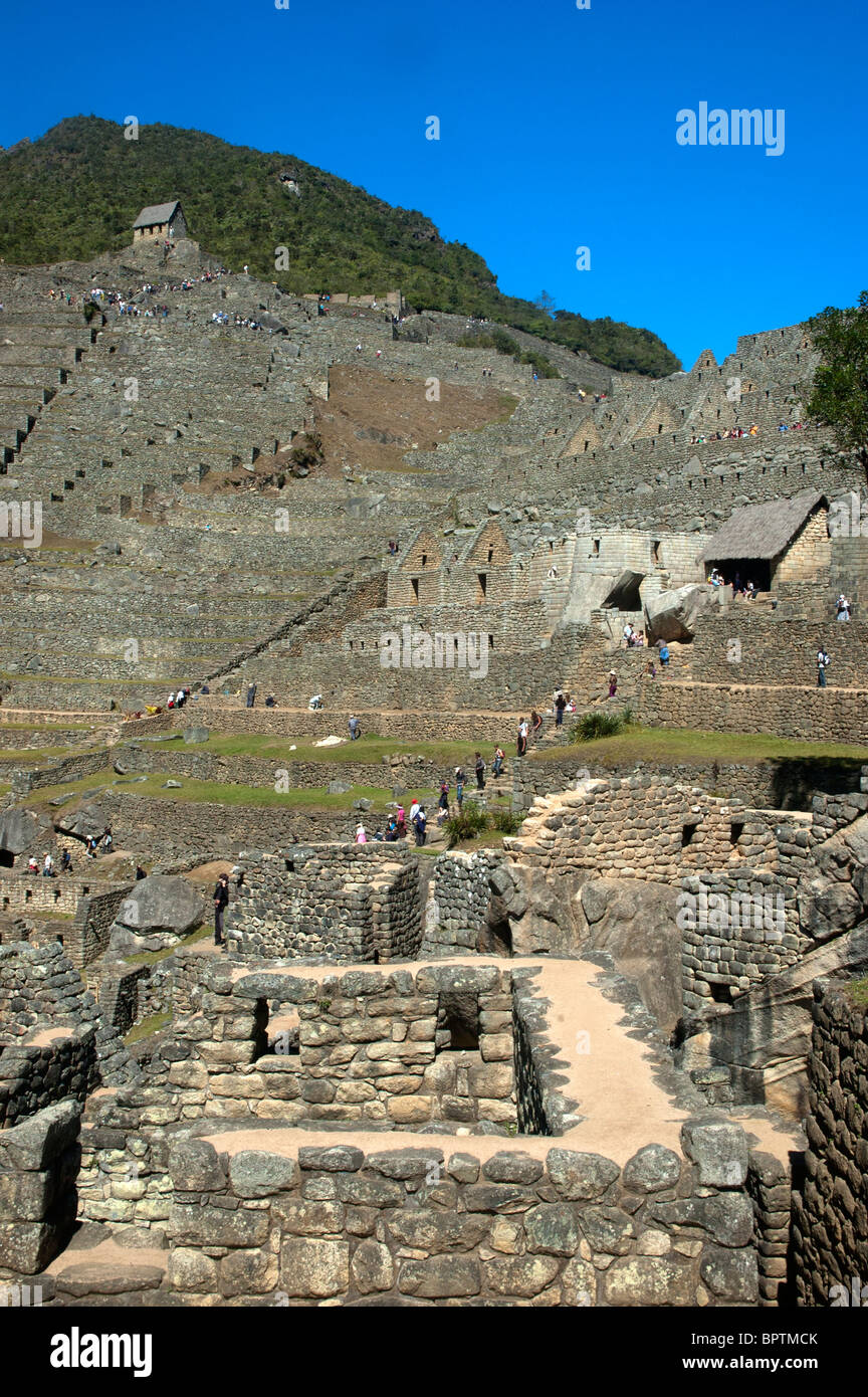 Tourists amidst the intricate stonework of ruined buildings and garden terraces at the ancient Incan city of Machu Picchu, Peru. Stock Photo