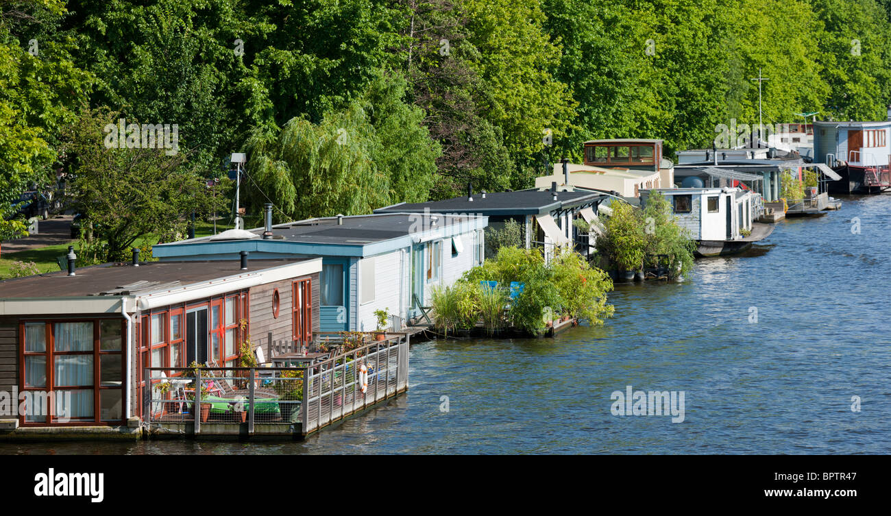 House boats in Amsterdam on the river Amstel, with floating gardens and decks or balconies. Stock Photo