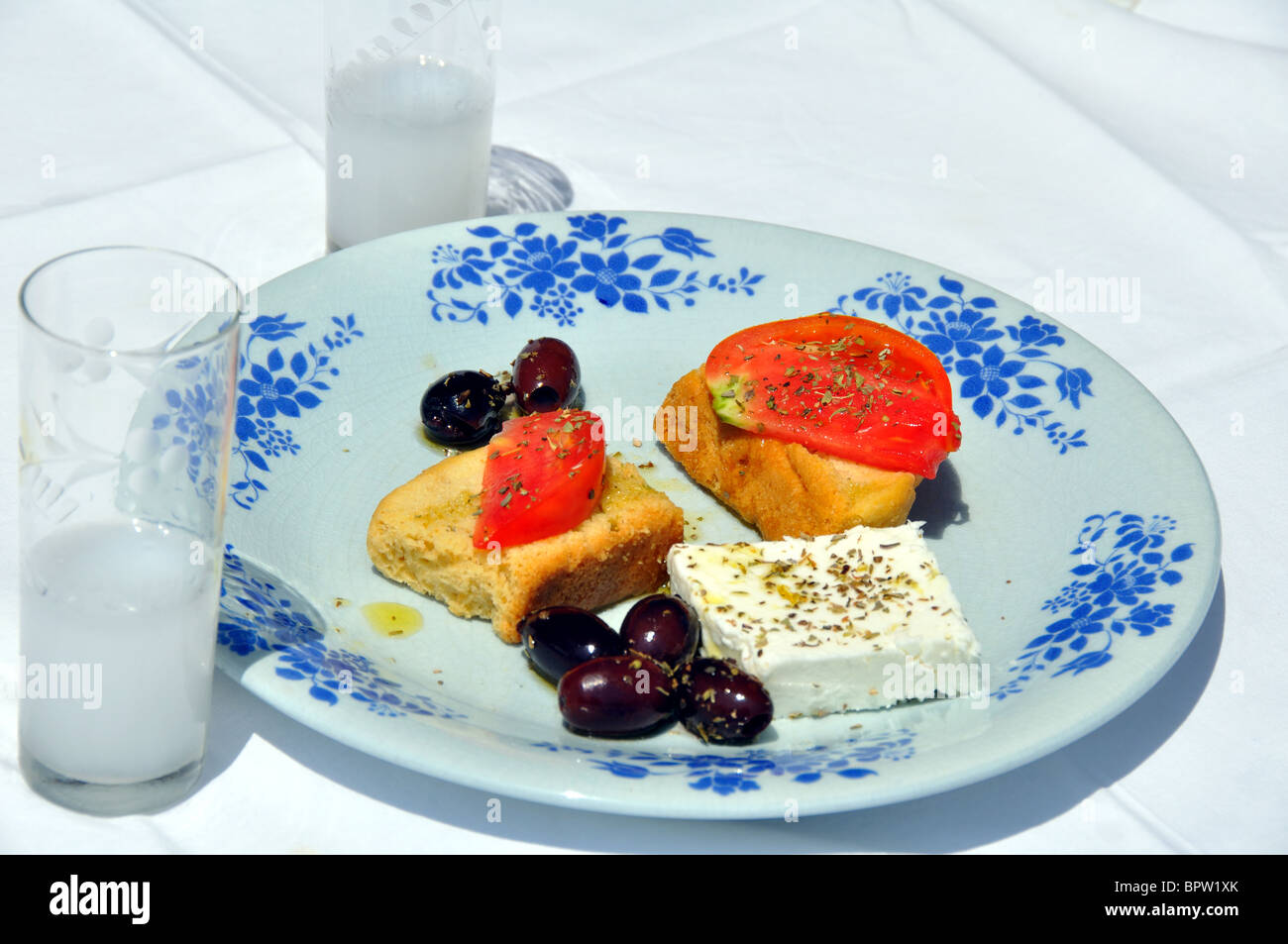 Greek Meze with Ouzo, Feta cheese, greek olives, tomatos on bread and oregano. Stock Photo
