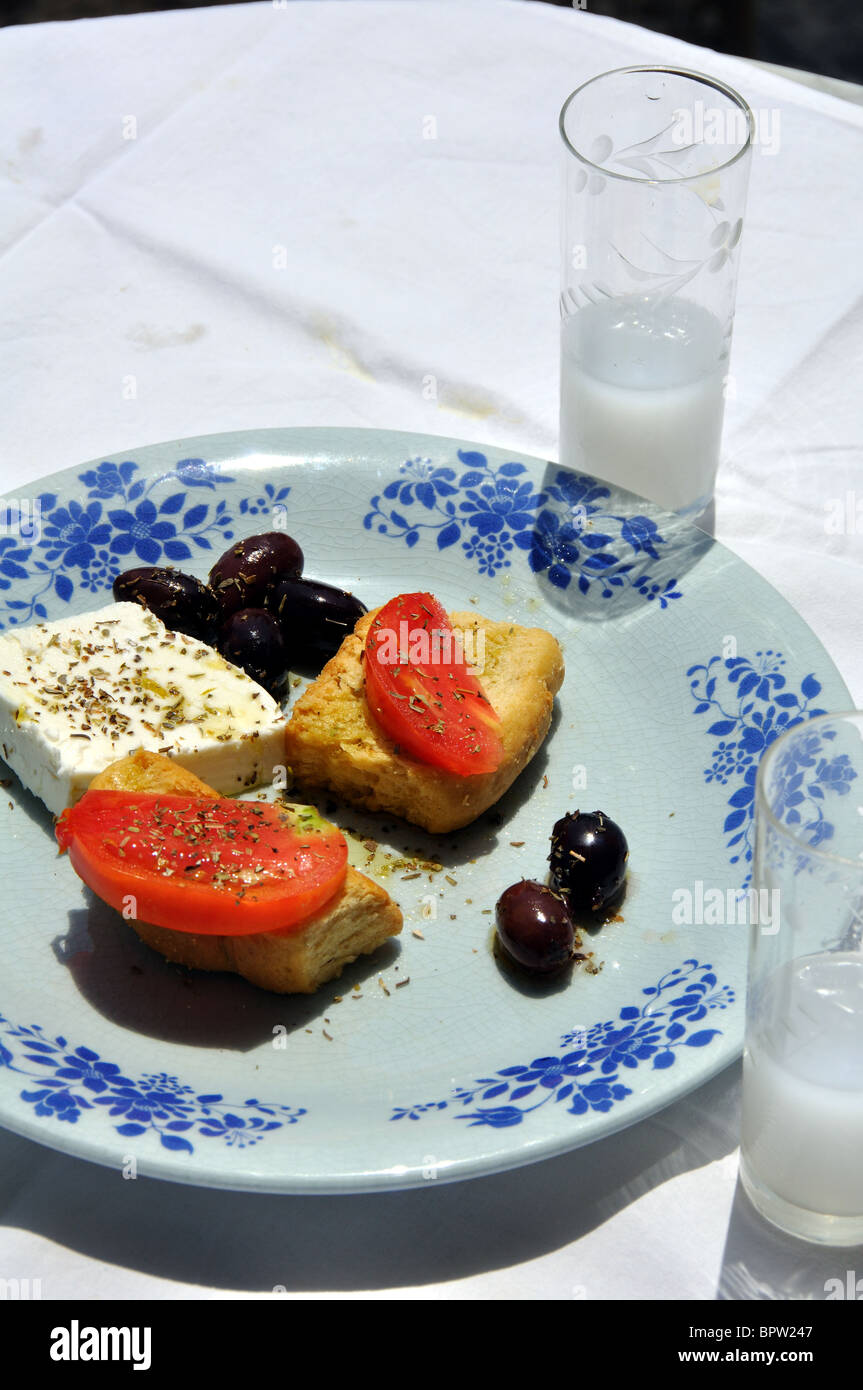 Greek meze with ouzo, feta cheese, tomatos on bread, greek olives, oregano. Stock Photo