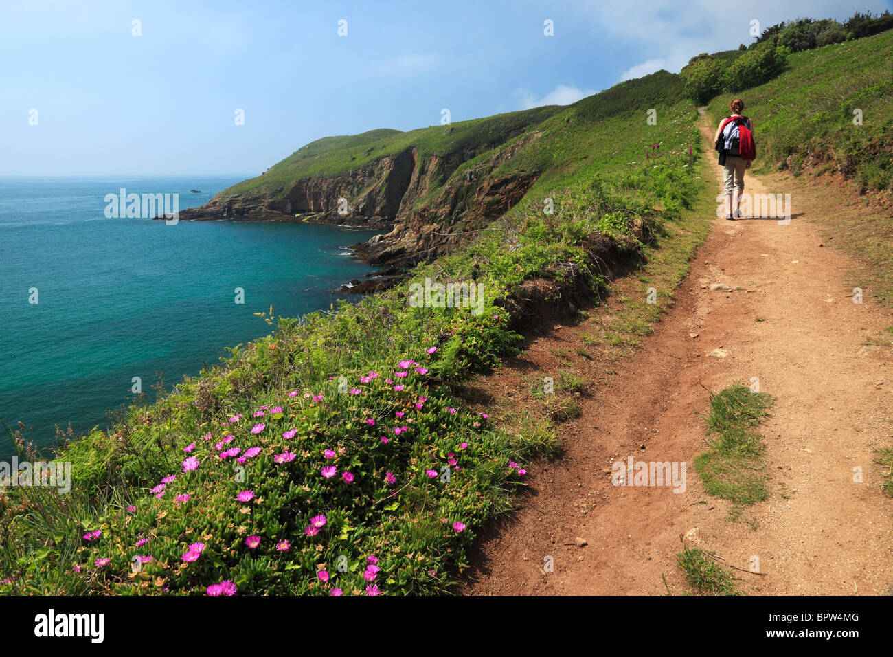 A woman hiking along the beautiful coastal path of North Herm in the Channel Islands of England Stock Photo