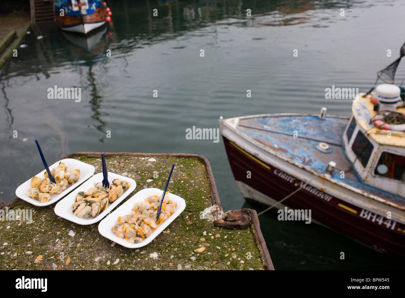 Whelks, Mussels and Cockles eady to eat by boats in a harbour. Stock Photo