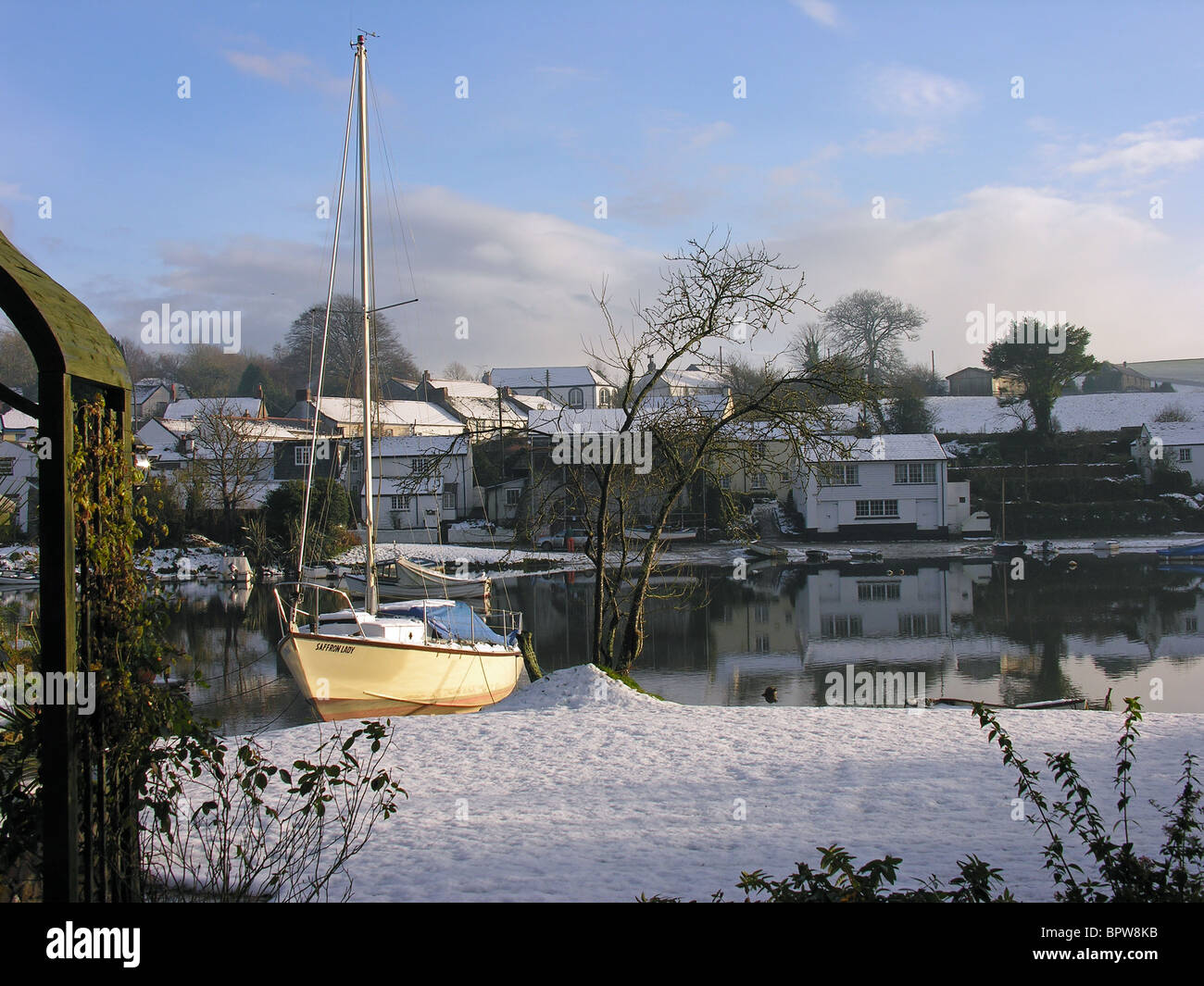 Snow cover on the banks of the River Lerryn and the houses beyond Stock Photo
