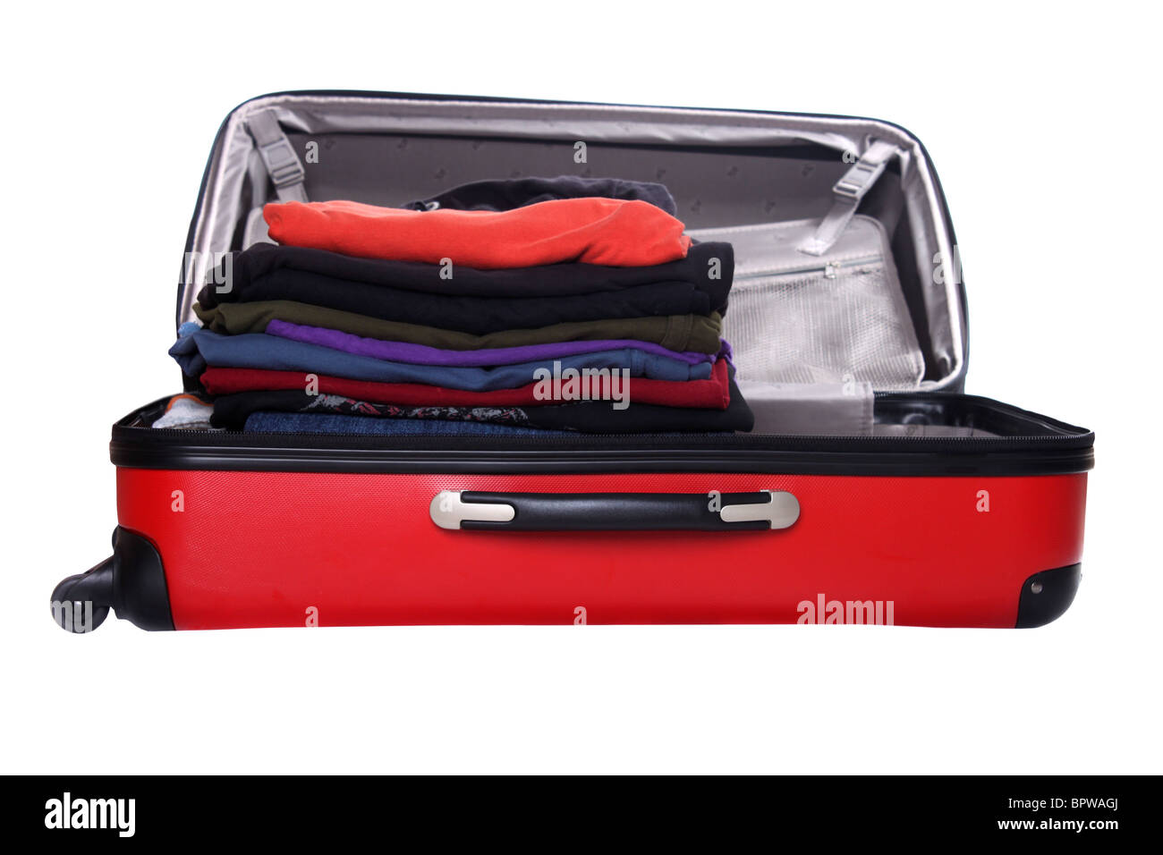 Clothes piled up while packing a hard shell red suitcase Stock Photo