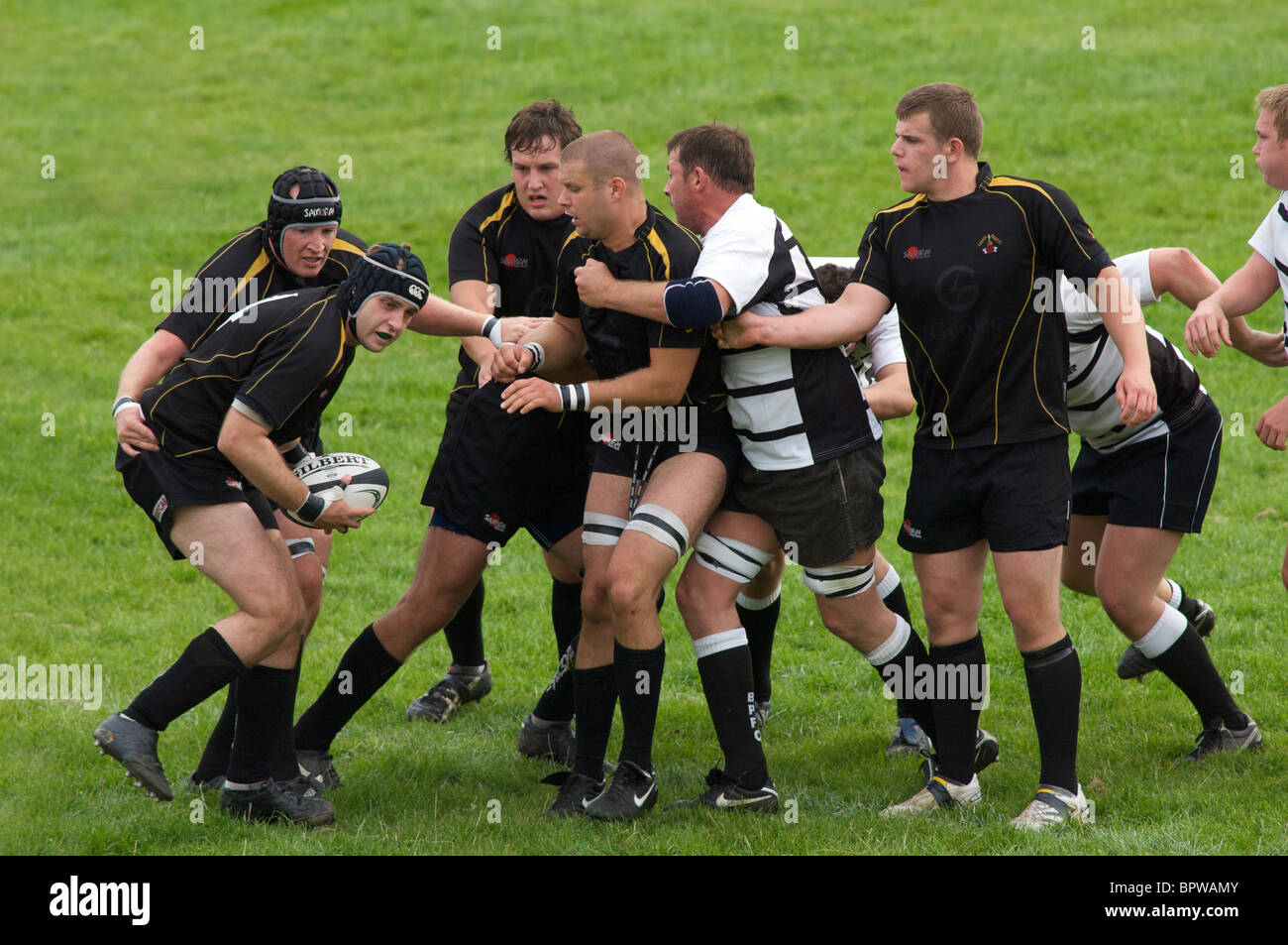 rugby player about to pass receives help from teammates Stock Photo