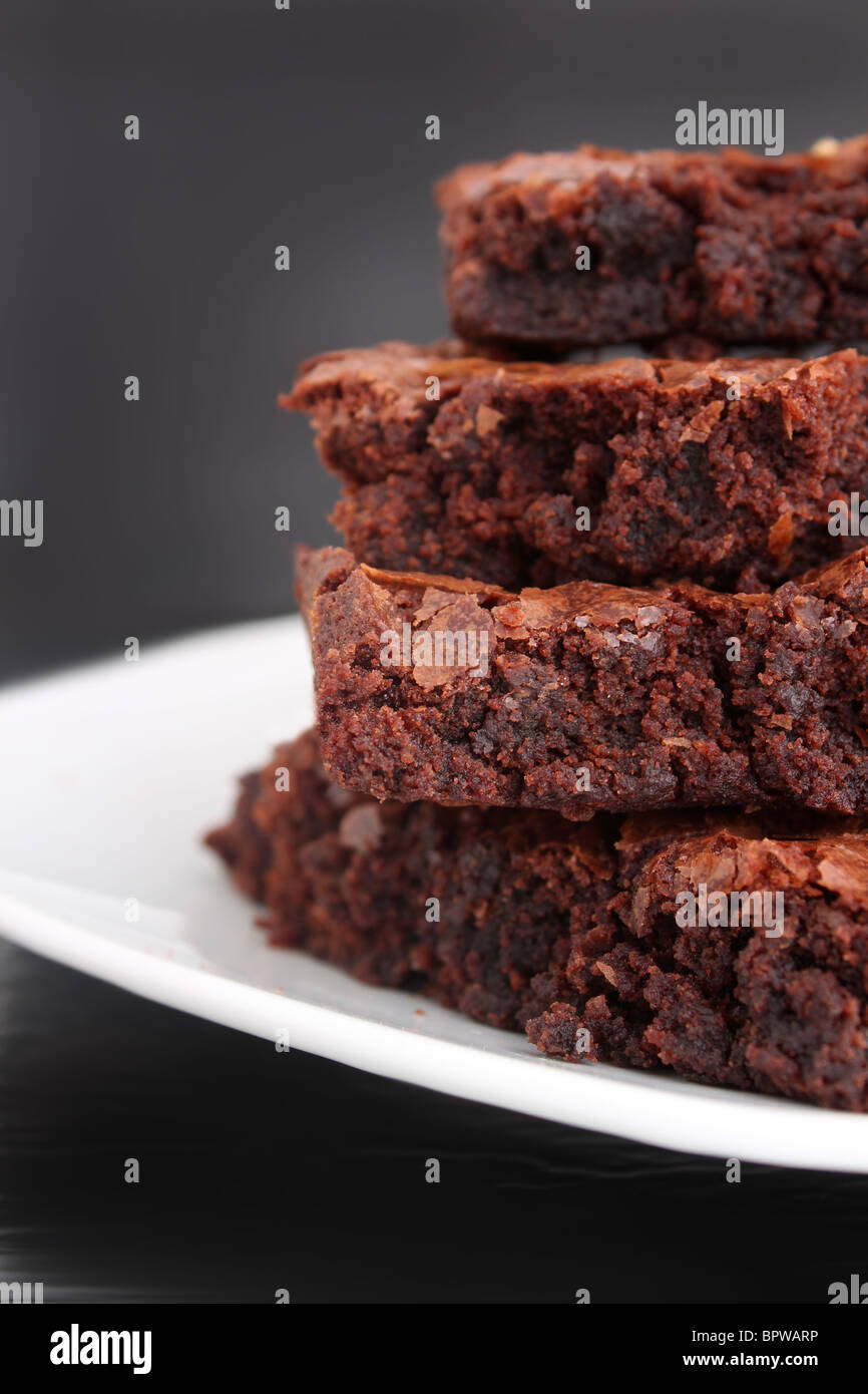 Pile of chocolate fudge brownies on a plate with a grey background (short depth of field) Stock Photo