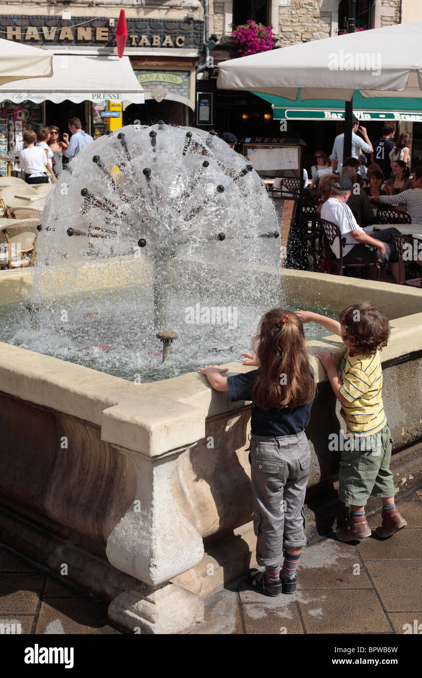 Two children playing by a fountain in Beaune, Burgundy, France. Stock Photo