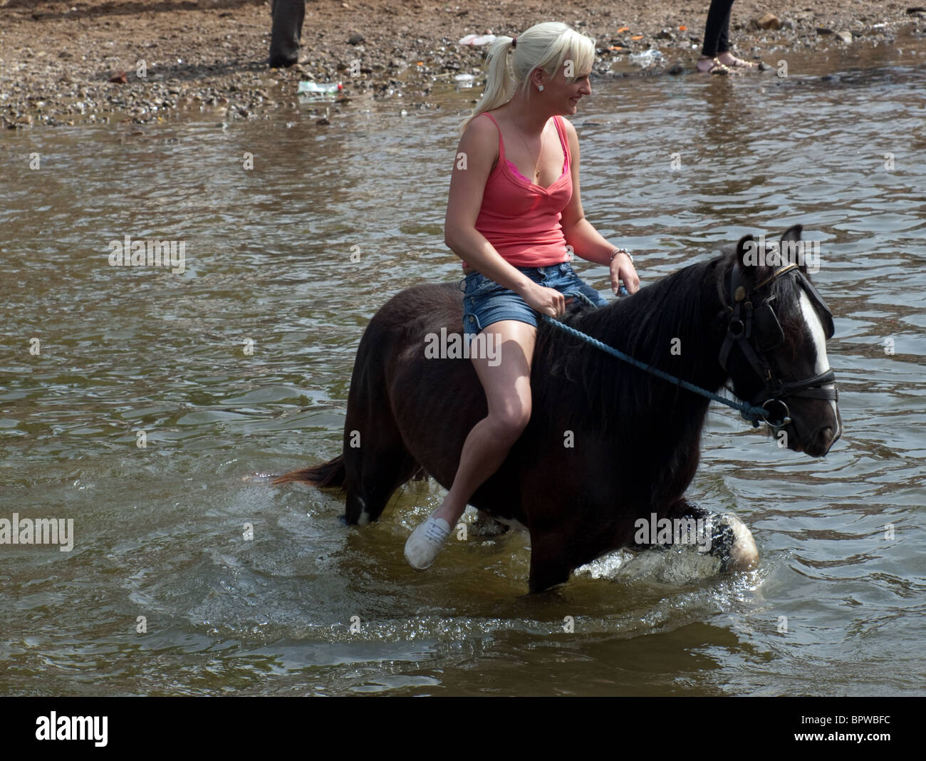 young woman in shorts and strappy tee-shirt riding horse bareback at the famous annual travellers' gathering at Appleby Horse Fair, Cumbria England UK Stock Photo