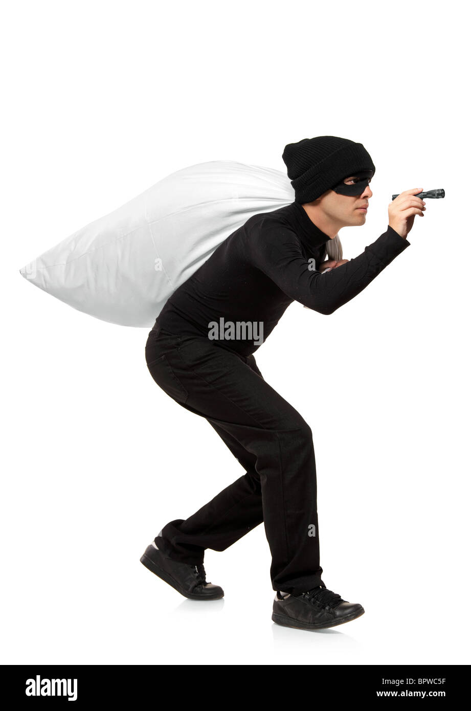 Thief carrying a bag and holding a torch Stock Photo