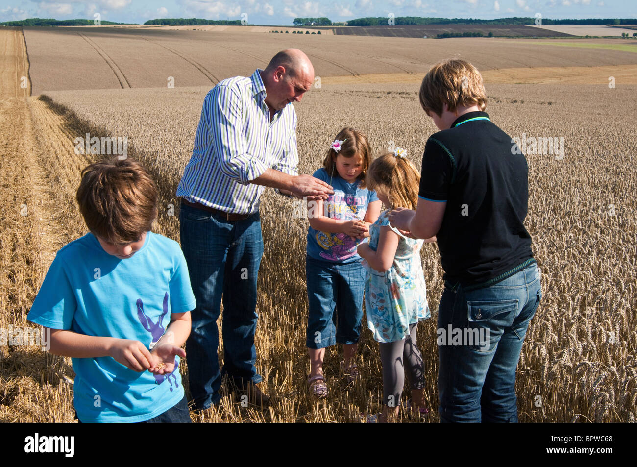 Farmer teaching children about wheat, where flour comes from. Stock Photo