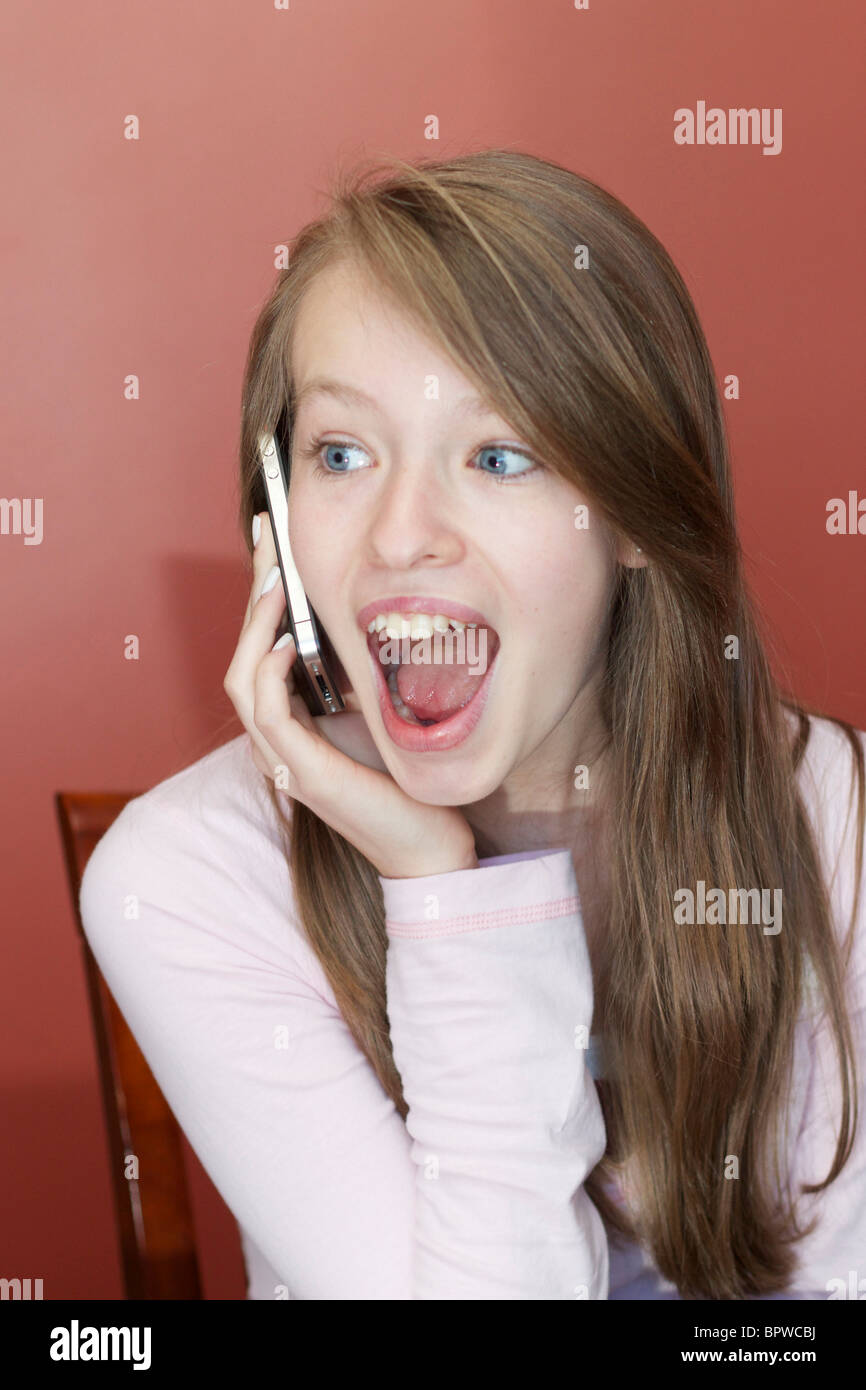 Thirteen year old girl talking on iPhone 4 with surprised facial expression. Stock Photo