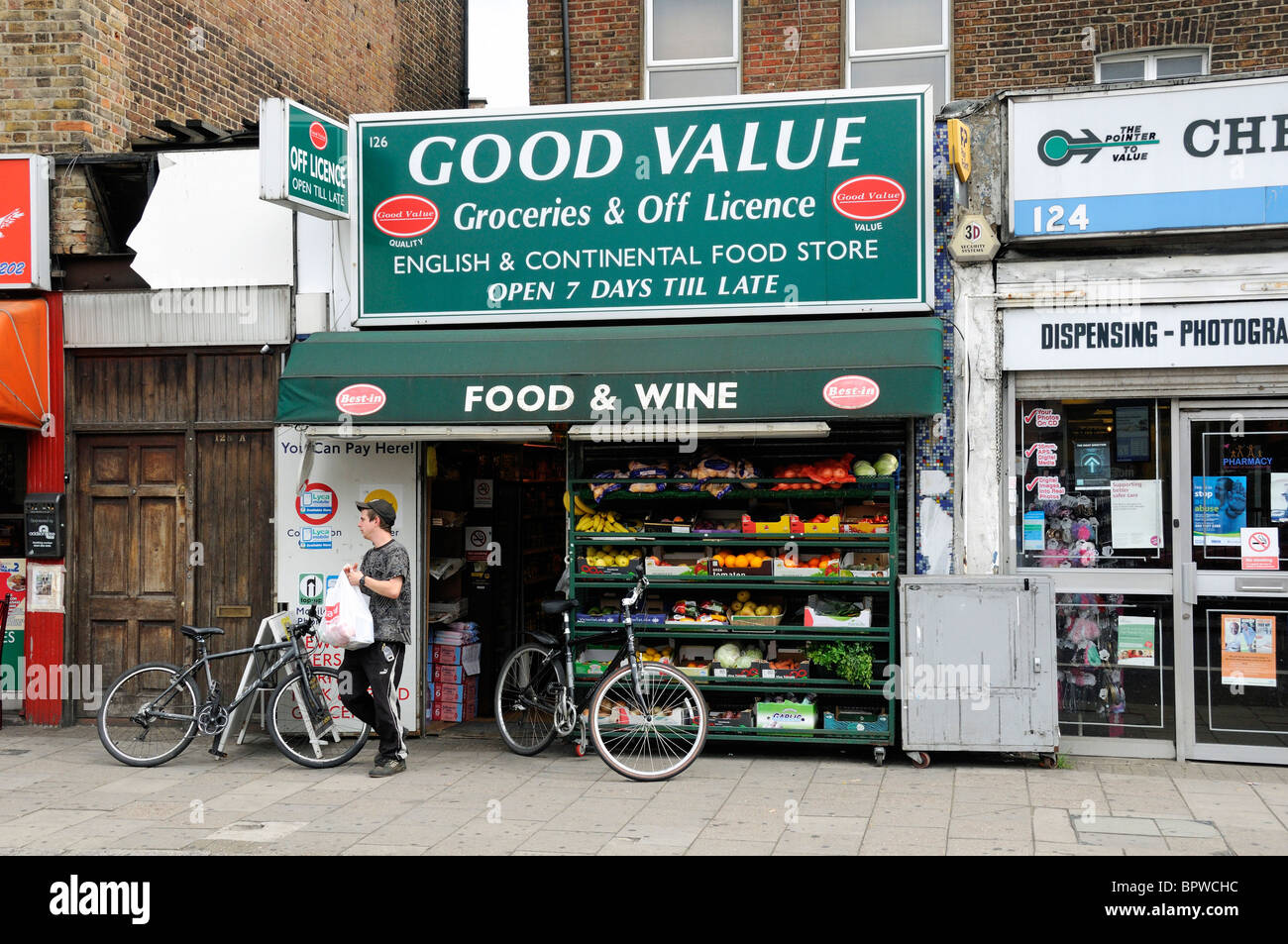 Man leaving Good Value a local groceries and off licence shop, Holloway Road Islington London England UK Stock Photo