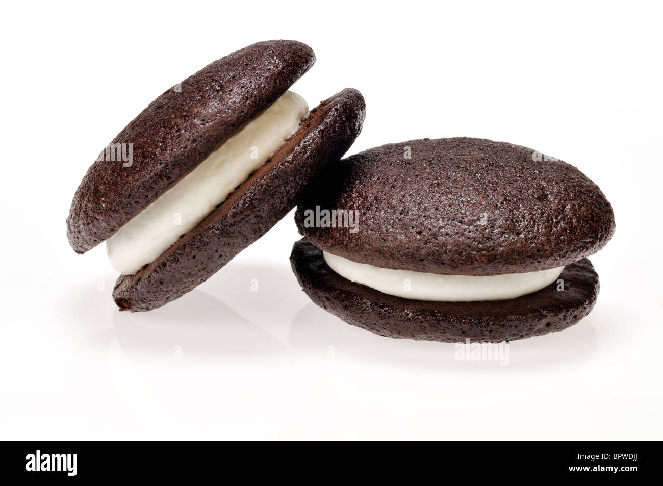 Two whoopie pie vanilla cream stuffed cakes on white background, cutout. Stock Photo