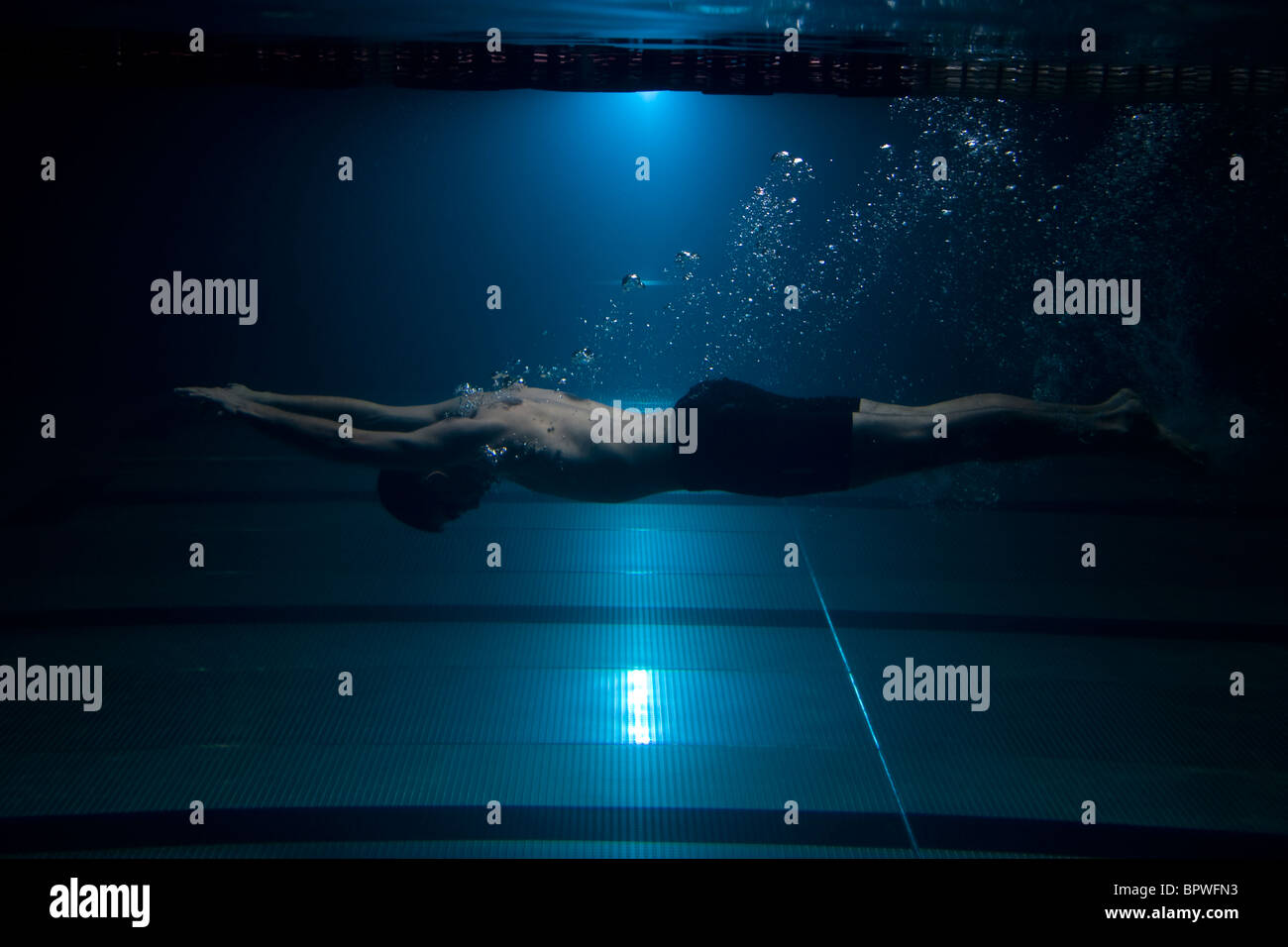 Swimmer swimming underwater exhaling bubbles on blue background Stock