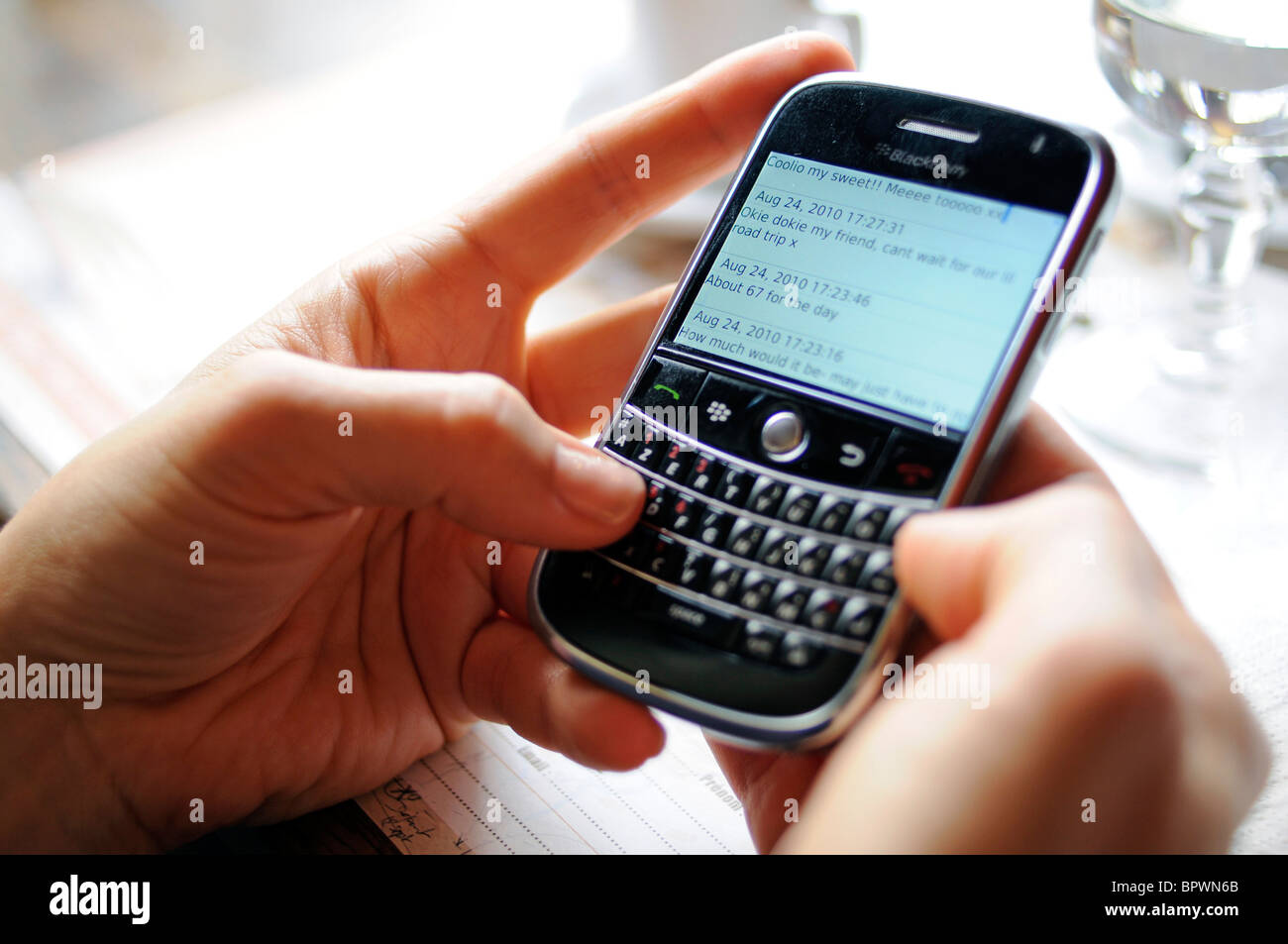 A woman using a Blackberry phone to send and receive emails and text messages over the Internet. Stock Photo