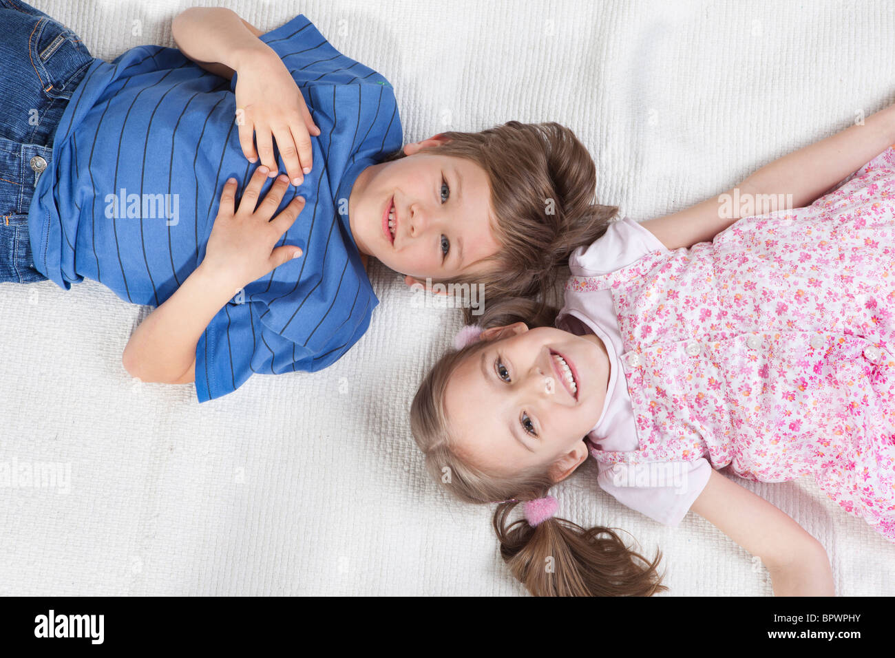 Brother and sister lying on rug Stock Photo