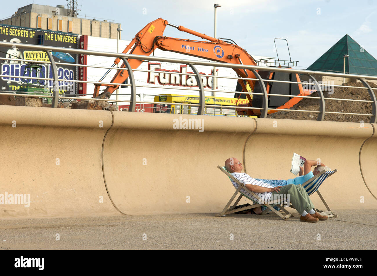 Senior couple relax in deck chairs on Blackpool promenade oblivious to