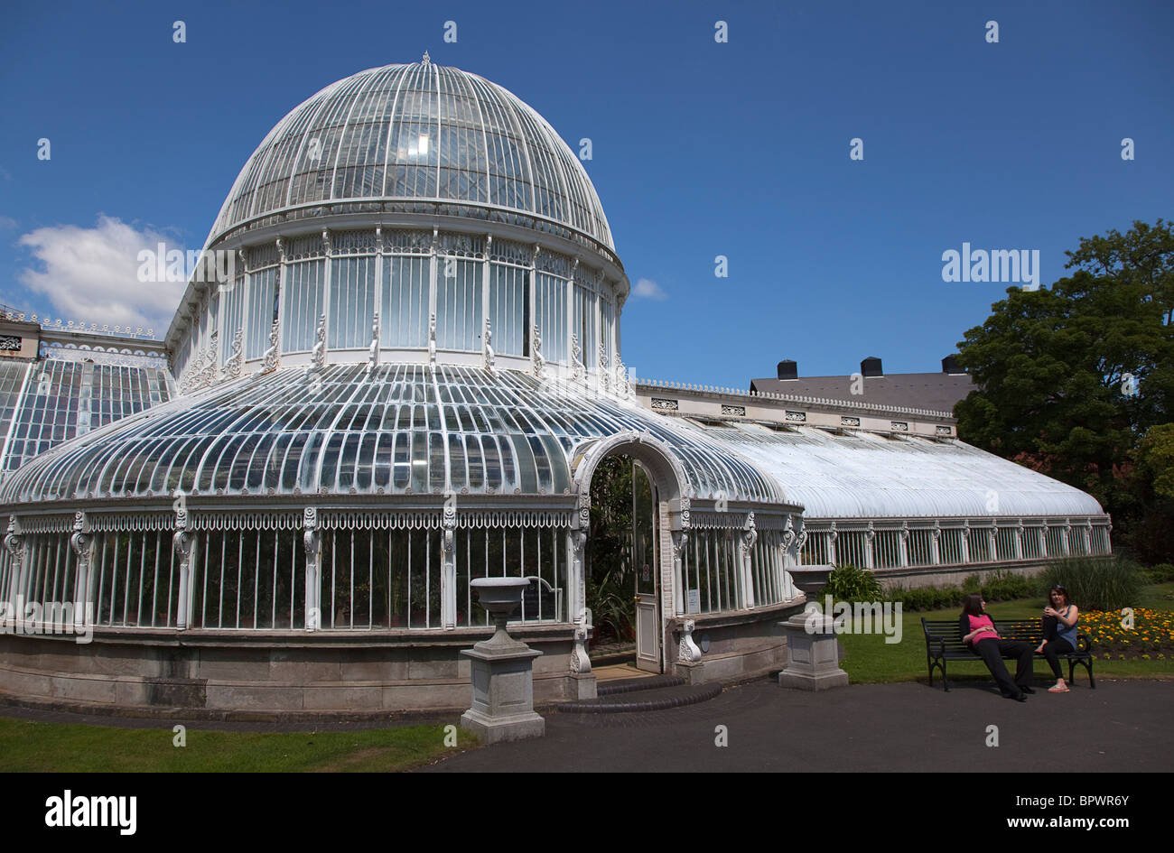 Ireland, Northern, Belfast, Botanic Gardens with people sat on benches outside the Palm House next to Queens University. Stock Photo
