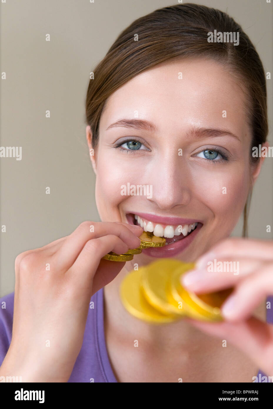 Woman bites on gold coins Stock Photo