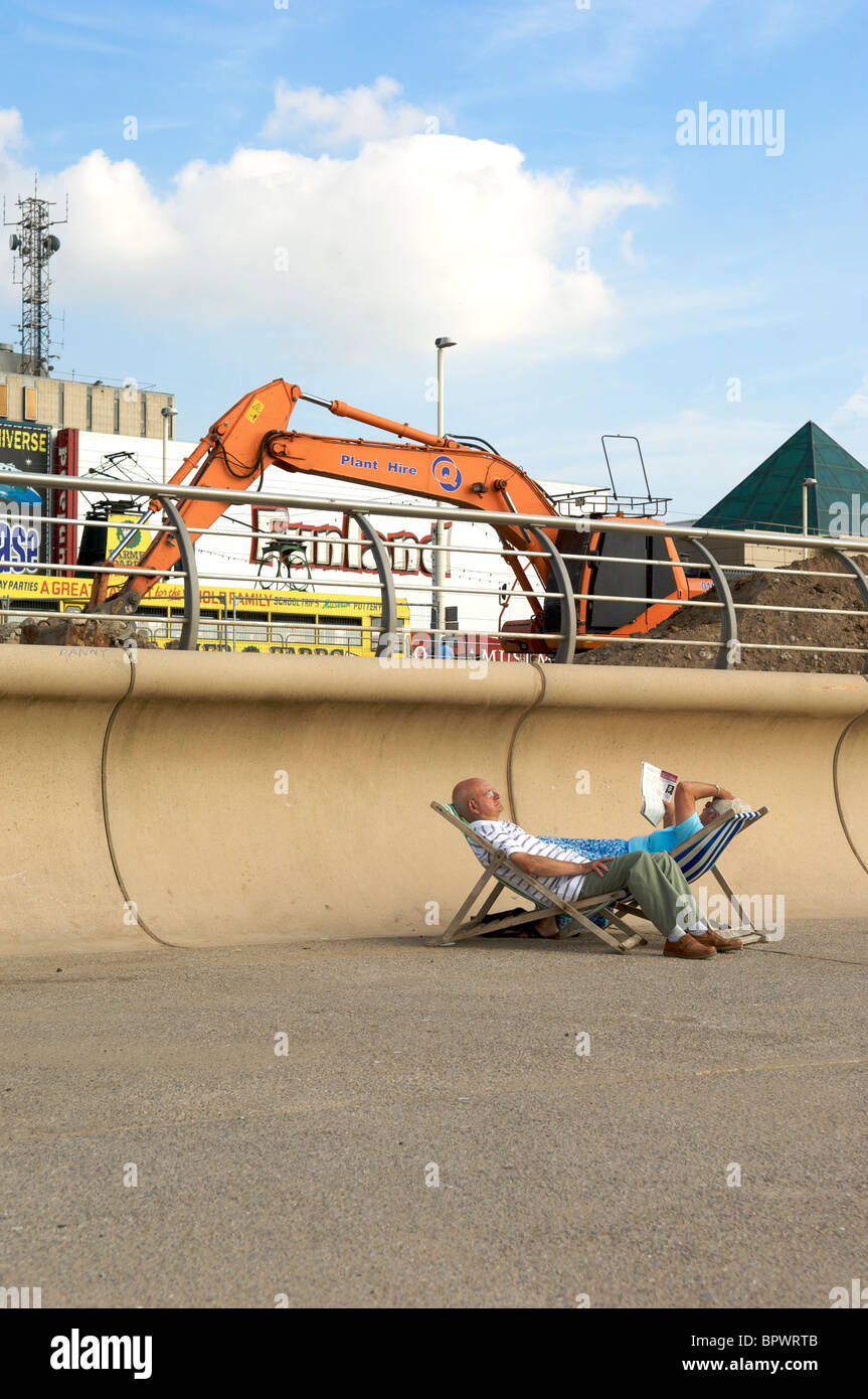 Senior couple relax in deck chairs on Blackpool promenade oblivious to