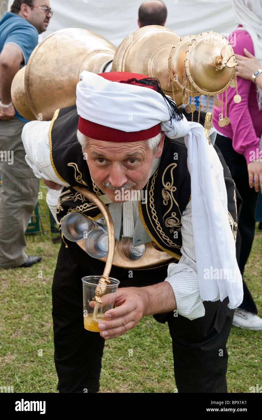 TURKISH MAN IN TRADITIONAL FOLCLORIC DRESS POURING SHERBET IN TO THE GLASS Stock Photo