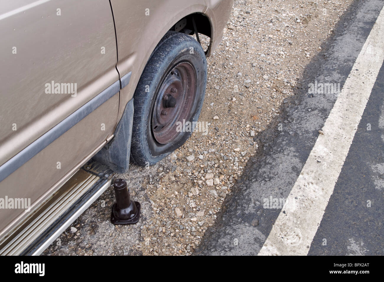 Flat tyre. Car with a flat tire pulled over by the side of the road on the soft shoulder. Stock Photo