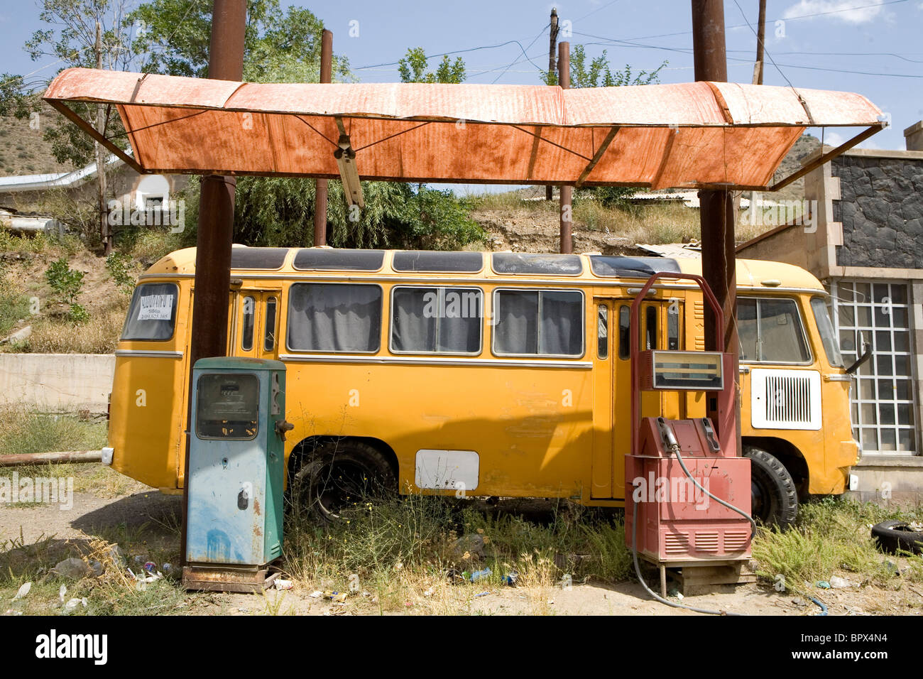 Travel Yellow Camper Van and Abandoned Old Petrol/ Gas in a Station with Red and Blue pumps in Armenia. Stock Photo