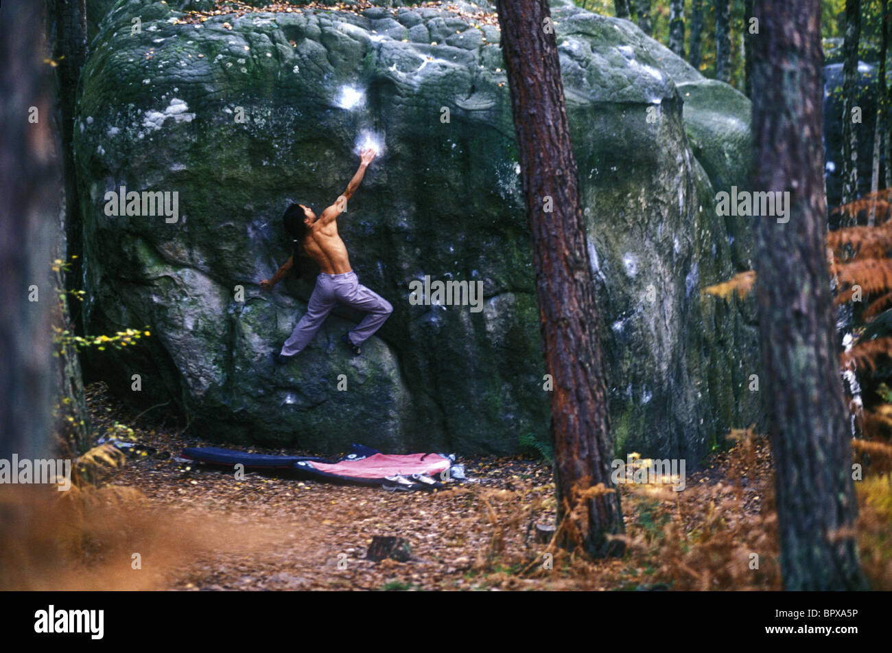 Asian male rock-climber climbing boulder Stock Photo