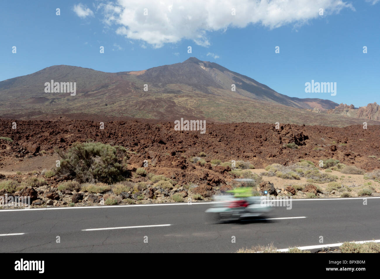 A Guardia Civil Trafico motorcyclist zooms past Teide in the Las Canadas del Teide National Park in Tenerife Canary Islands Stock Photo