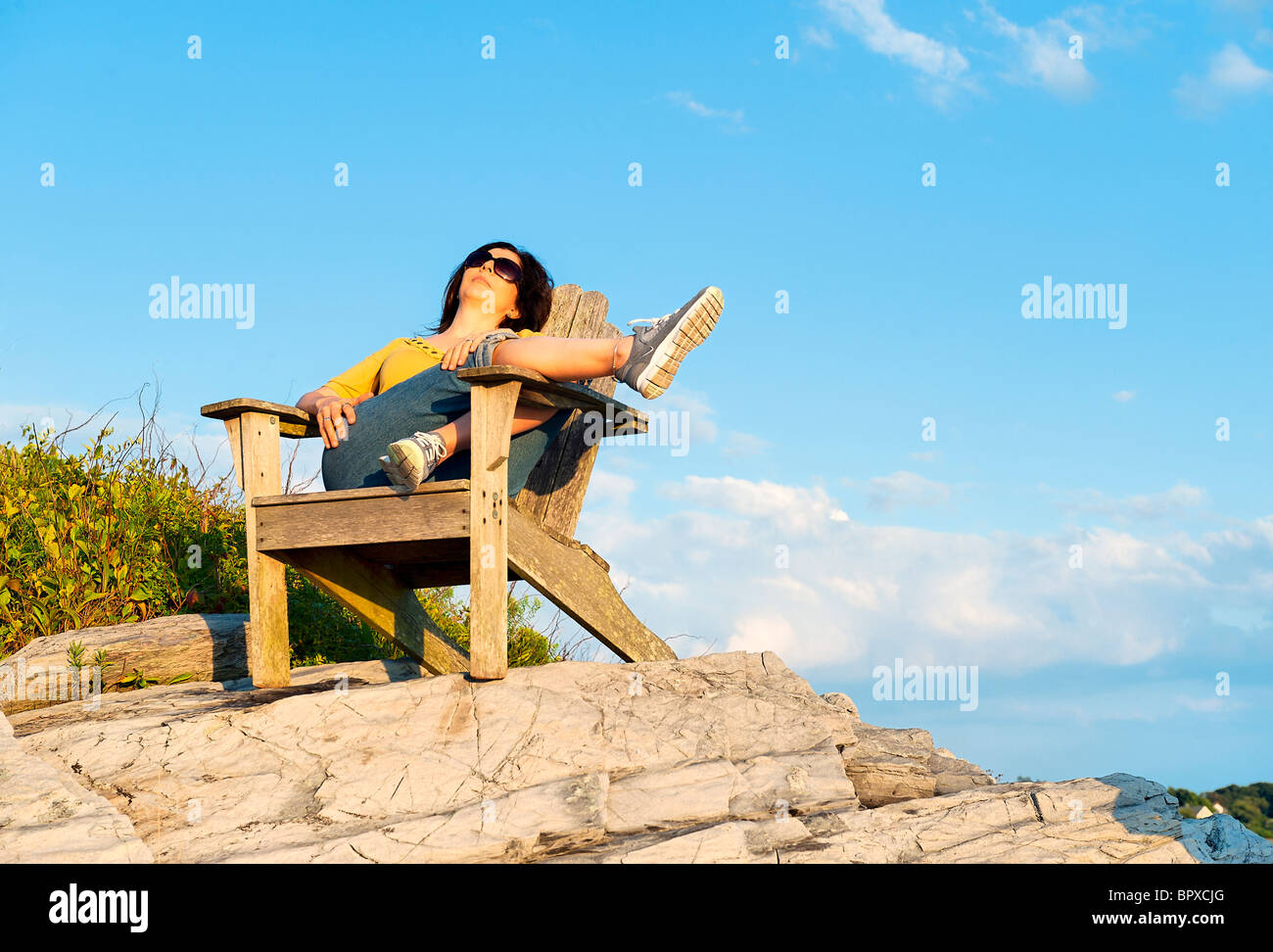 Woman enjoys the coastal view while relaxing in an Adirondack chair. Stock Photo