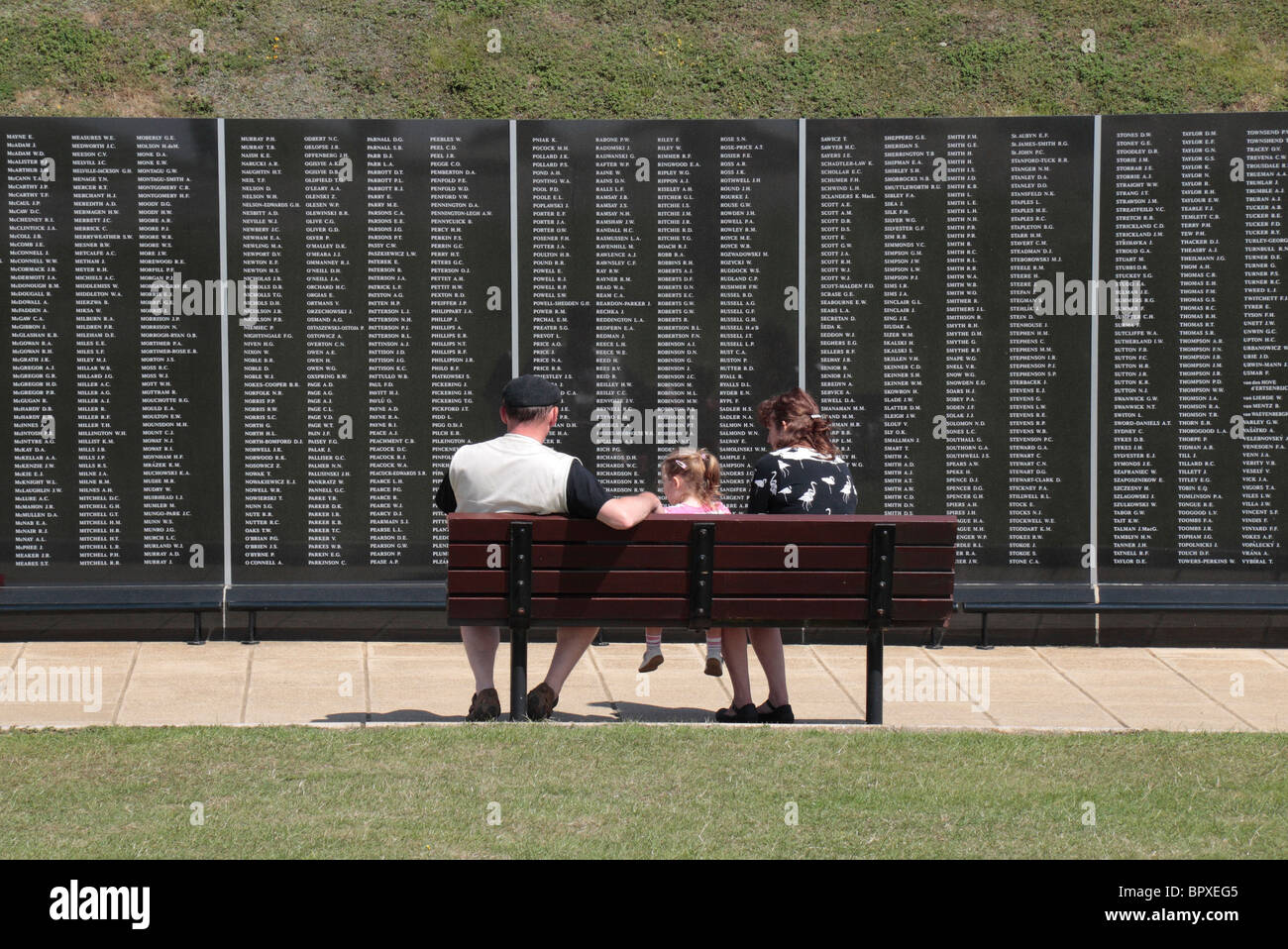 A family sitting in front of the Christopher Foxley-Norris Memorial wall, Battle of Britain Memorial, Capel le Ferne, Kent, UK. Stock Photo