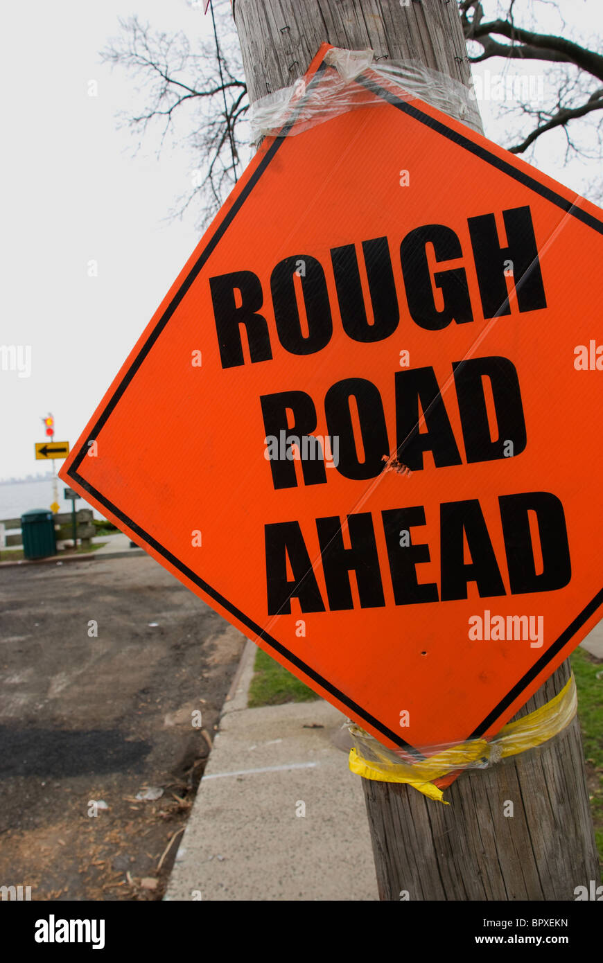 close up of orange diamond shaped sign reading 'Rough Road Ahead' Stock Photo