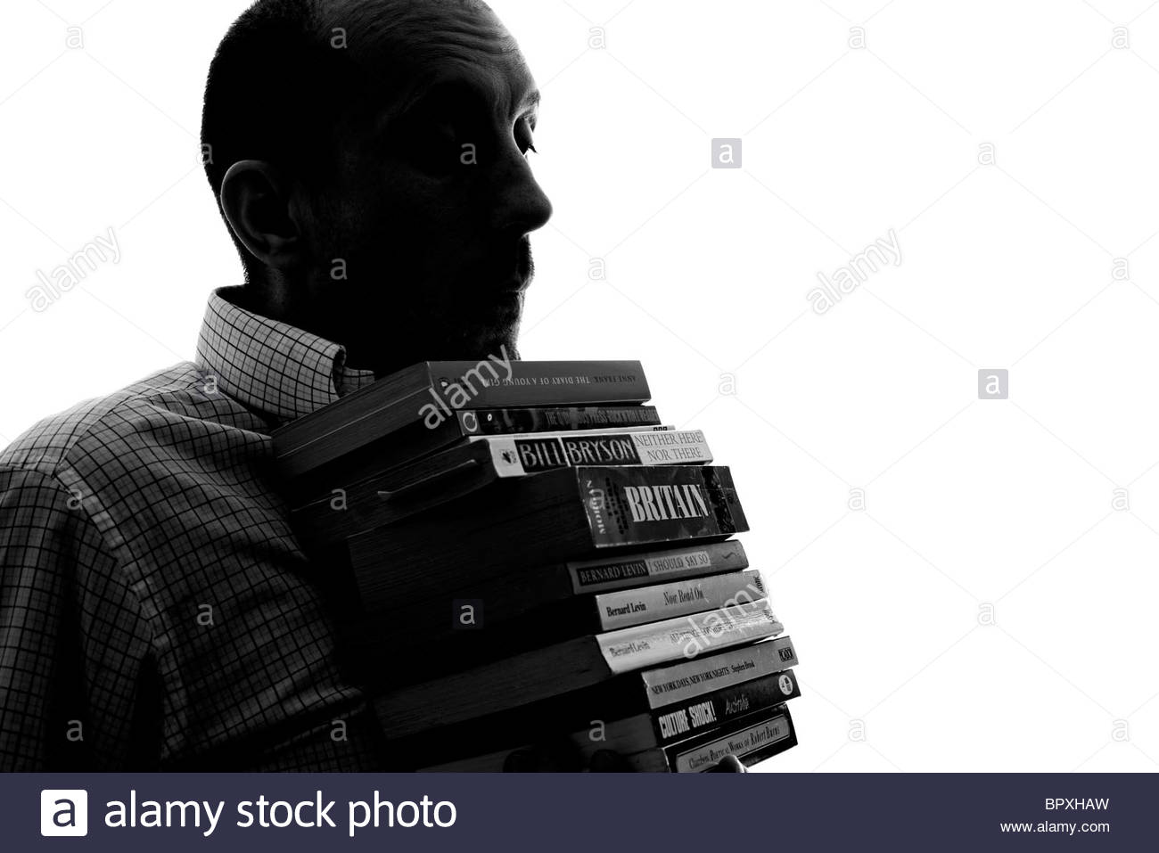 Silhouetted man carrying books Stock Photo
